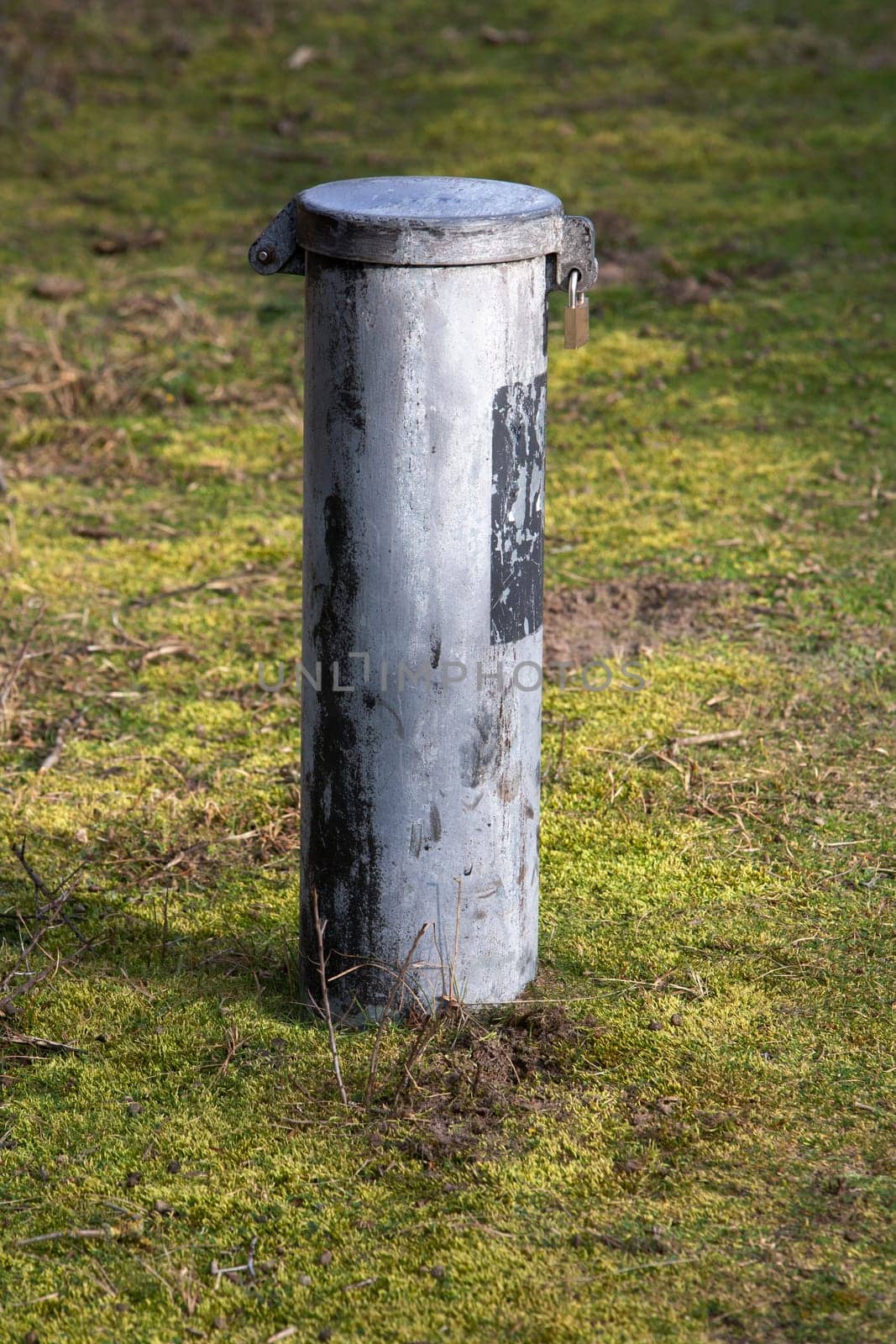 Metal cylinder container with a padlock in nature.