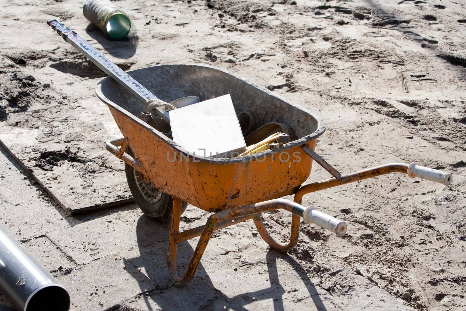Orange wheelbarrow with tools on a construction site