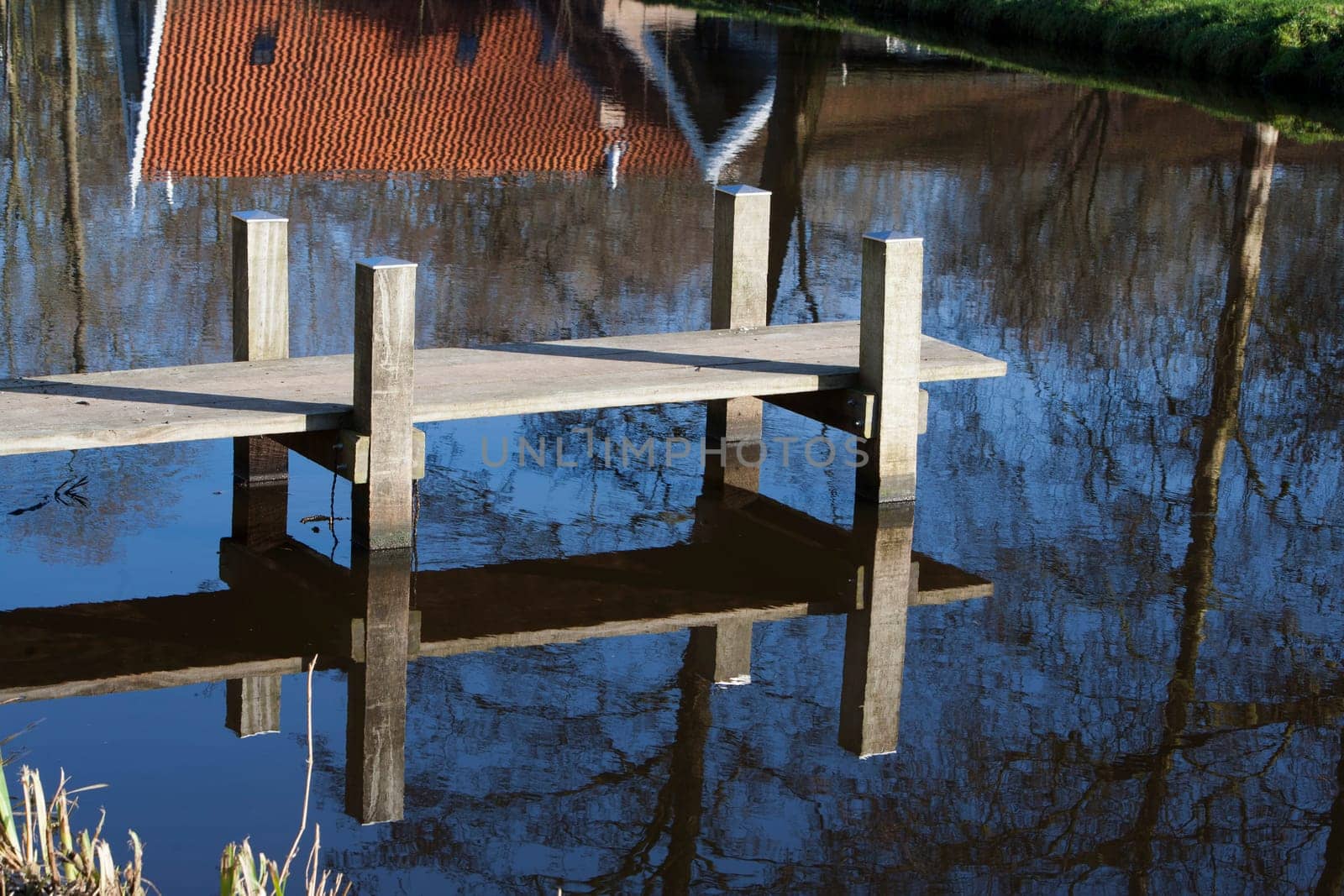 Jetty near a farm, reflected in the water