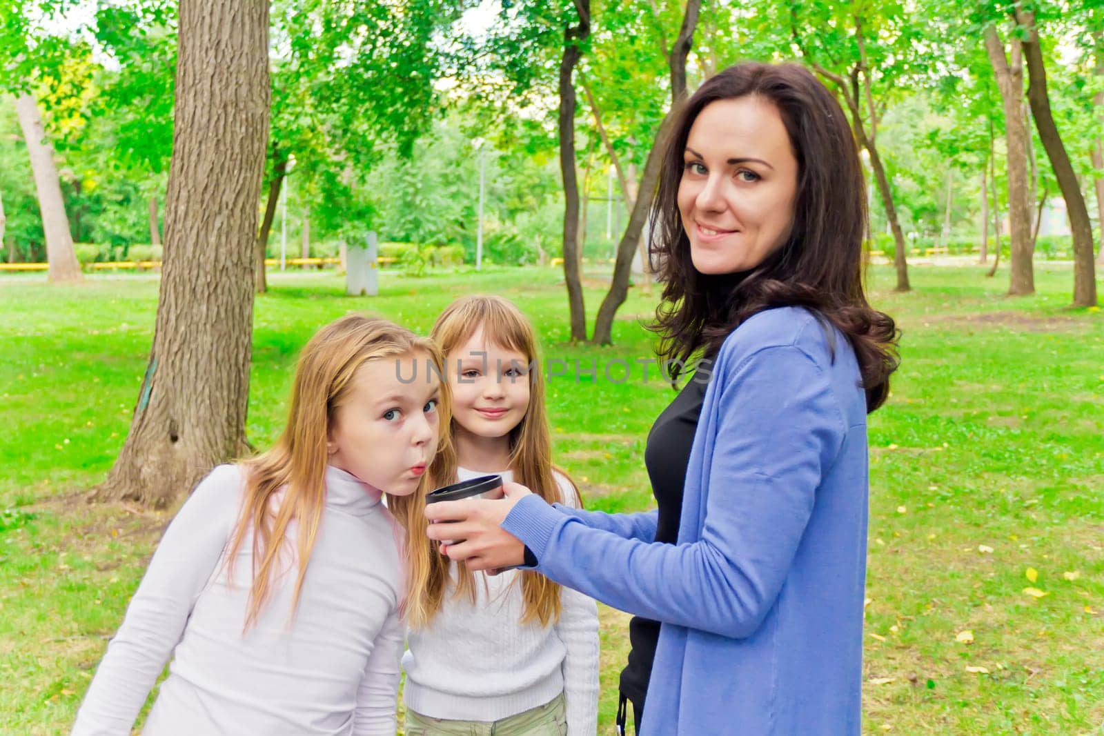 Photo of woman with two girls drinking tea