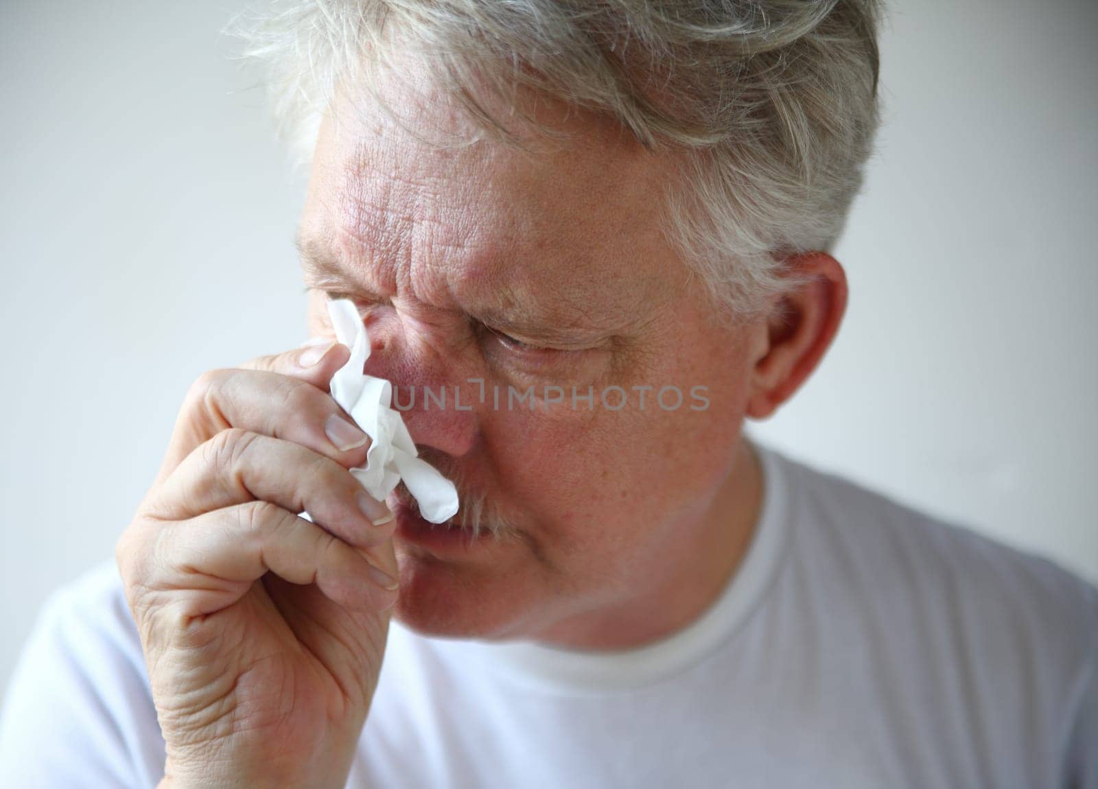 A man with the flu or a cold wipes his runny nose.