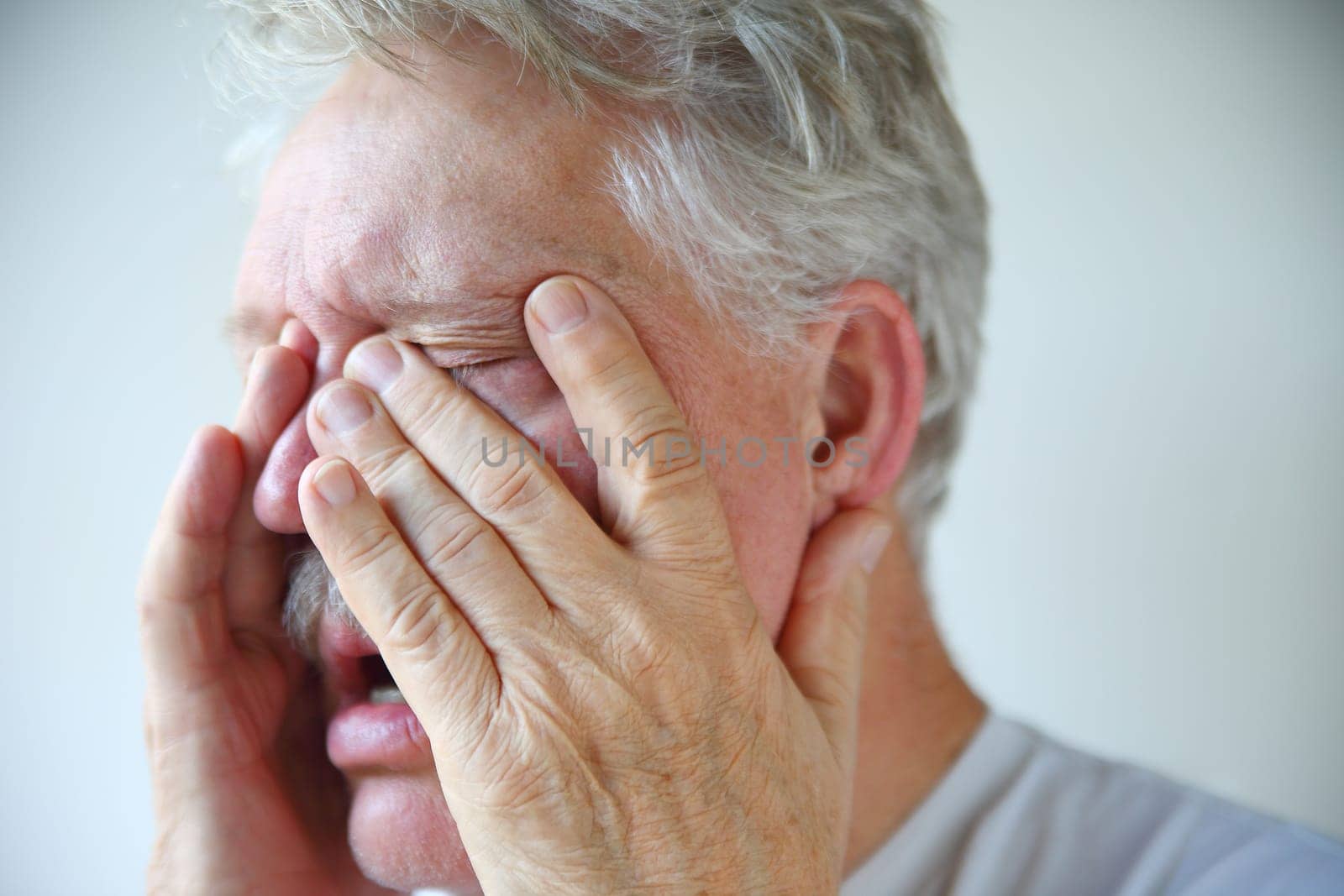A senior man experiencing stuffy nose, clogged sinuses and headache of a bad flu or cold