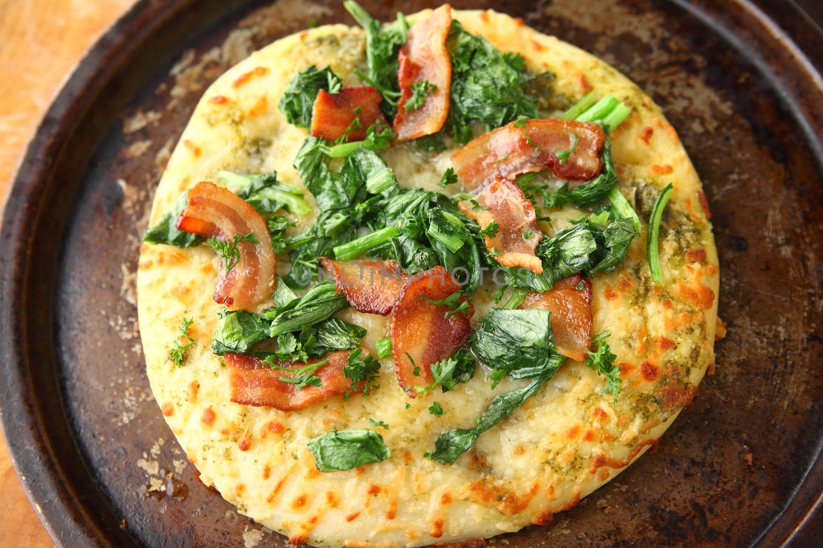 Pizza with bacon, leafy greens and parsley on an old pan