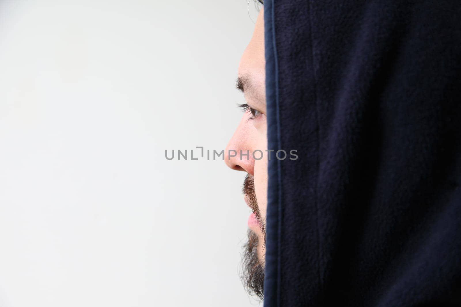 Profile of a young man wearing a black hooded jacket with copy space