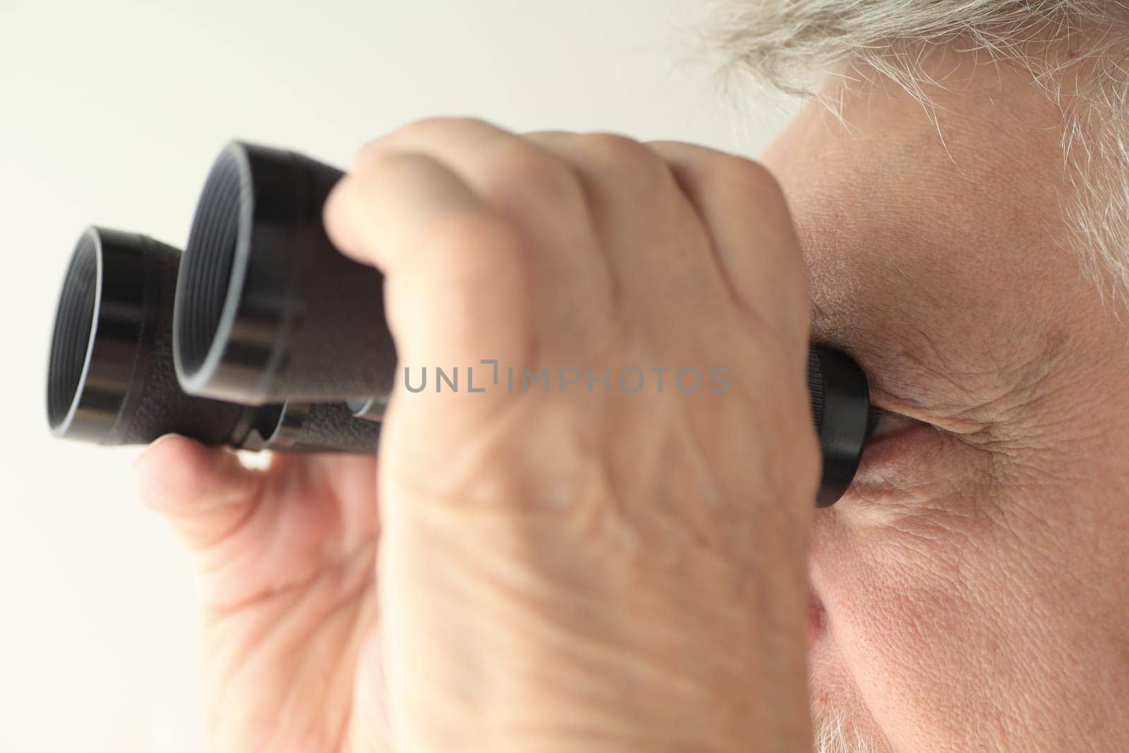 An older man looking through an old pair of binoculars