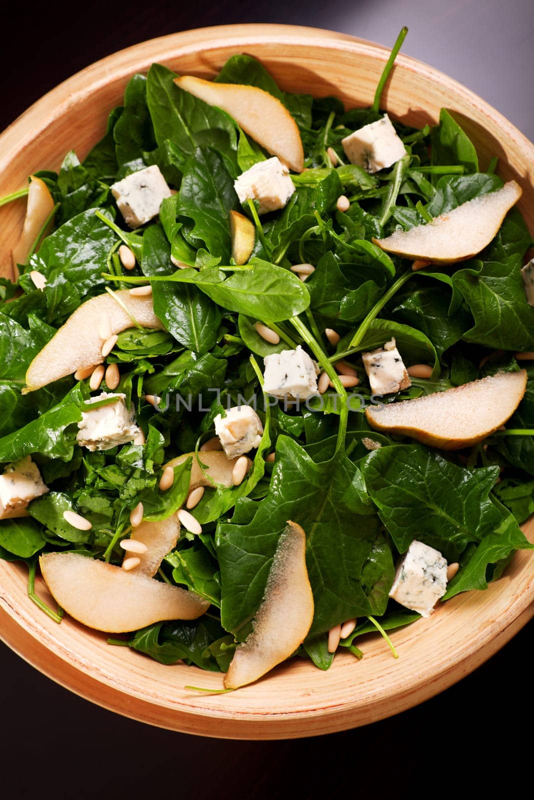 Fresh spinach salad with blue cheese, pears and honey served in a salad bowl, close up