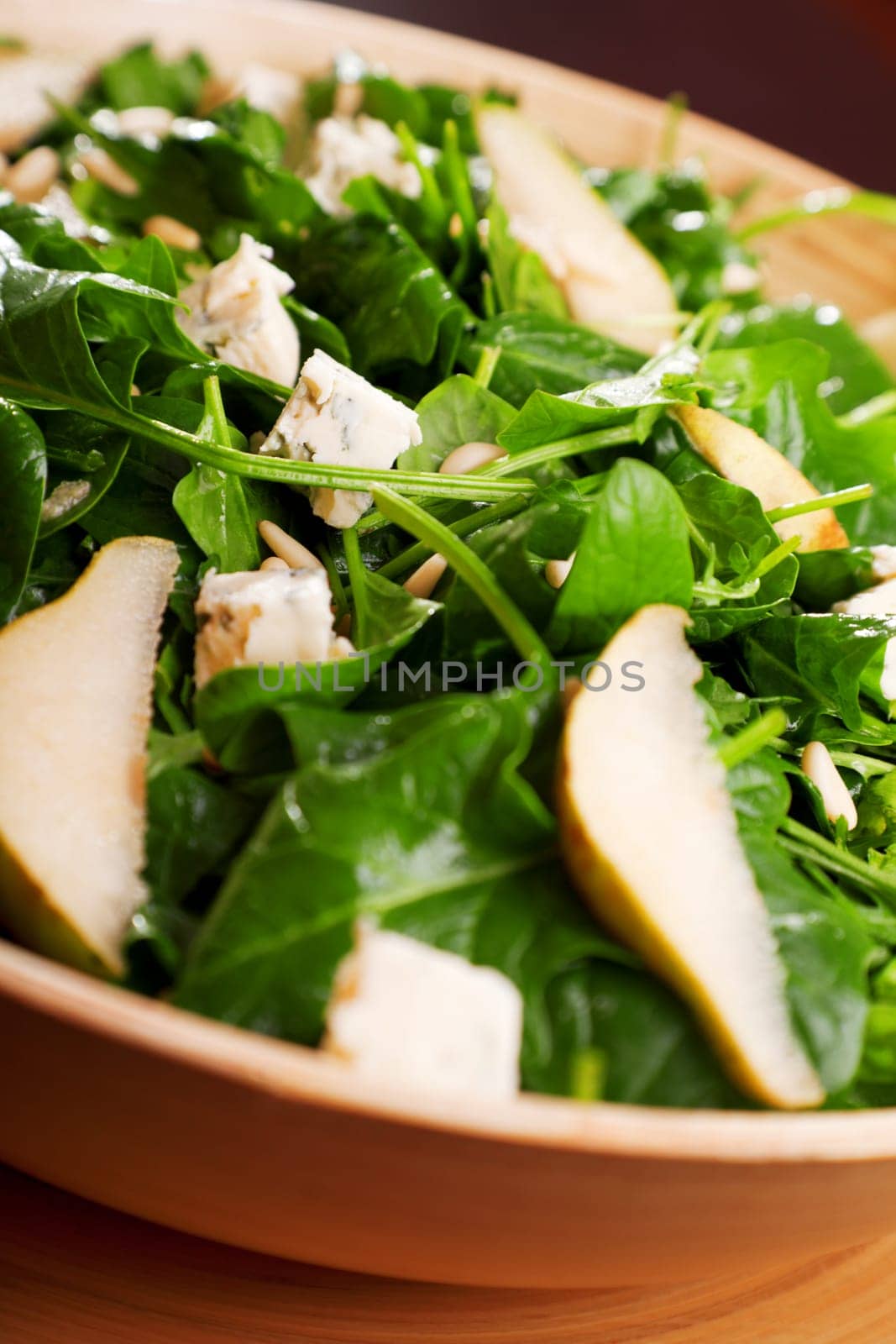 Fresh spinach salad with blue cheese, pears and honey served in a salad bowl, close up