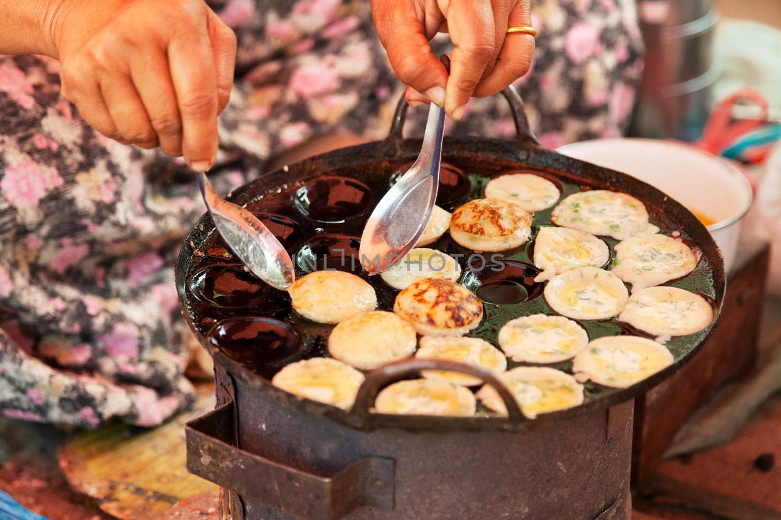 Old Burmese woman cooking street food at five-day market while sitting on the ground