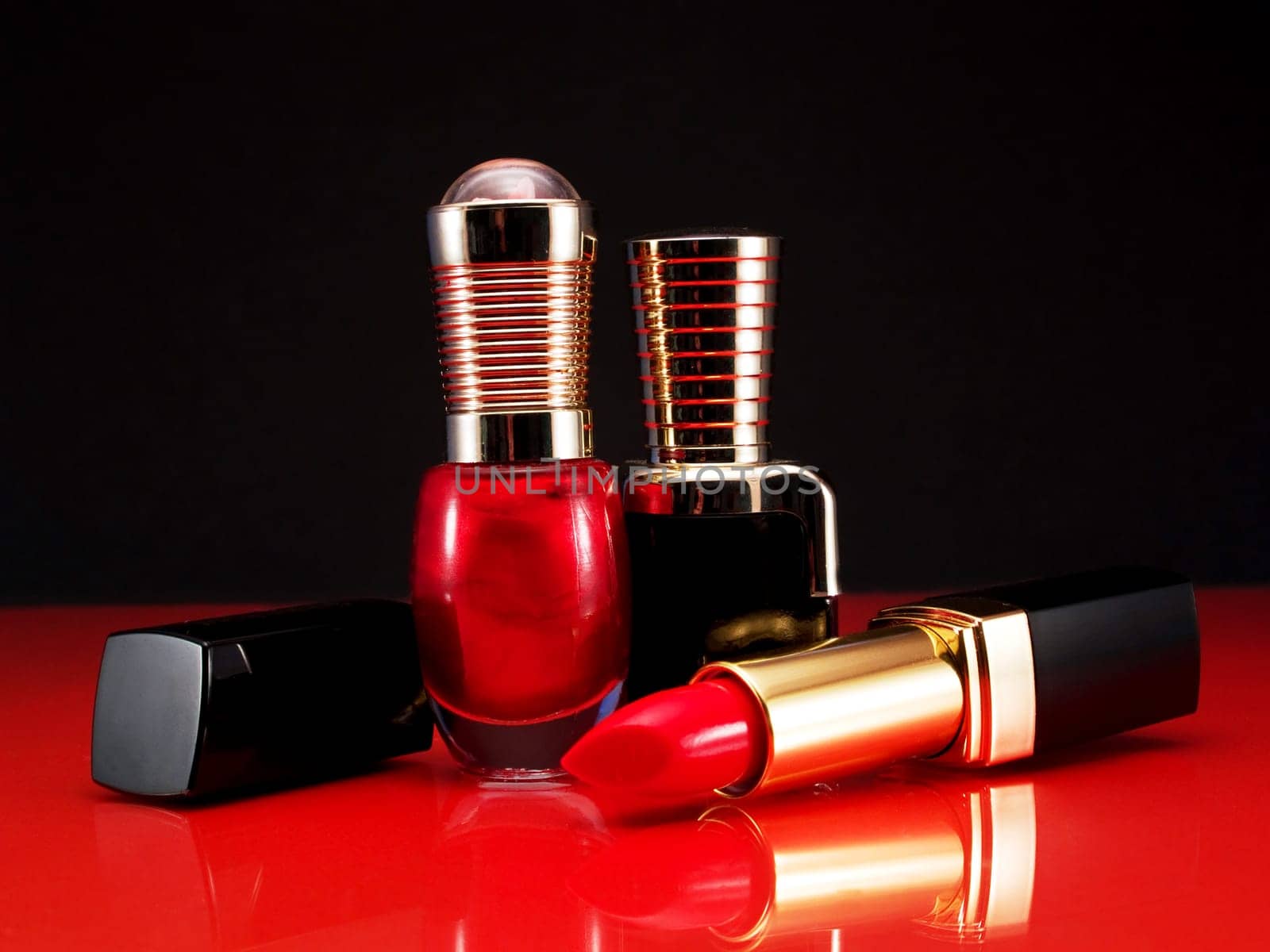 Red listick and nail polish shot over reflective background