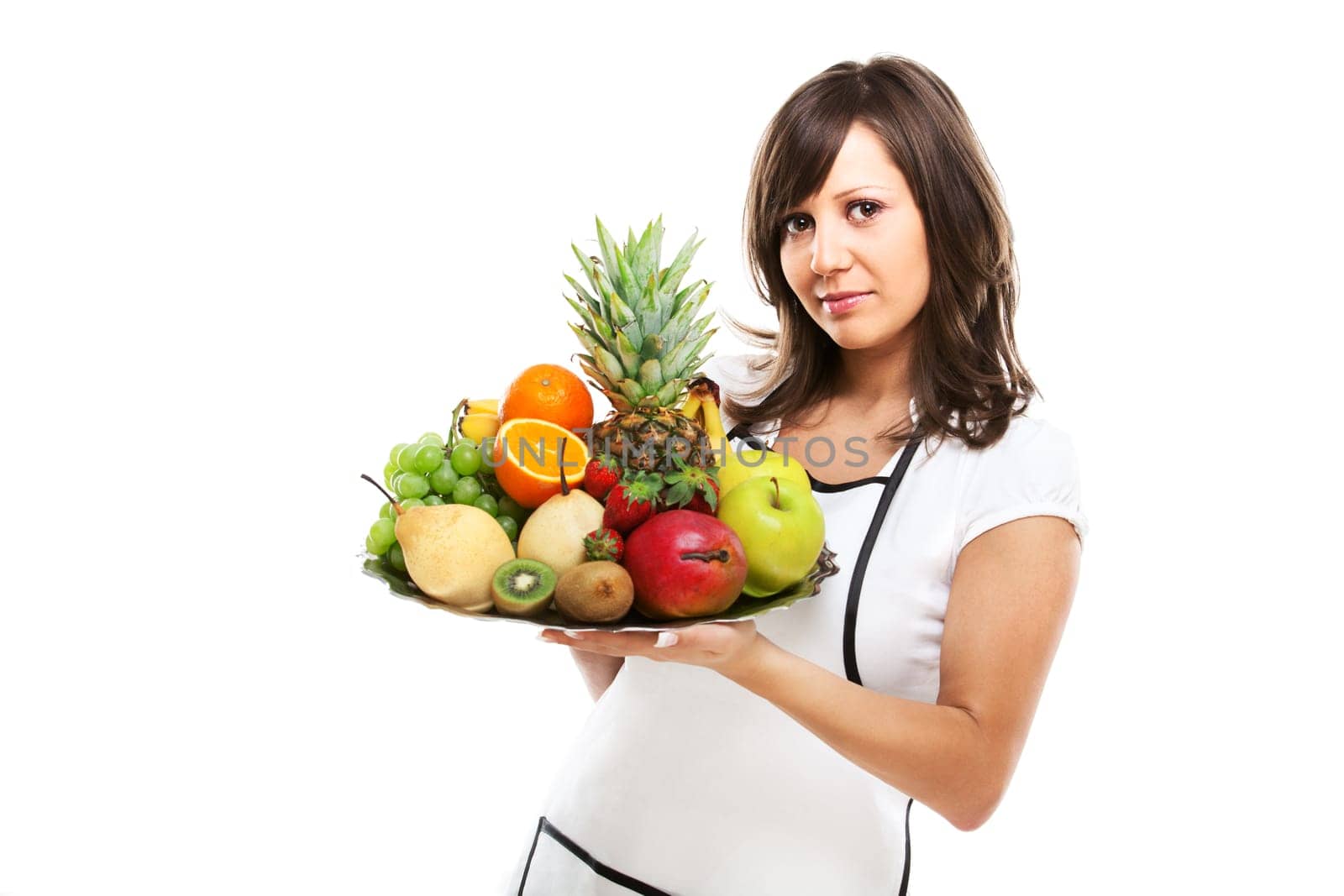 Young woman holding a tray with fresh fruits - apples, pears, grapes, pineapple, oranges, kiwi, strawberries and others.