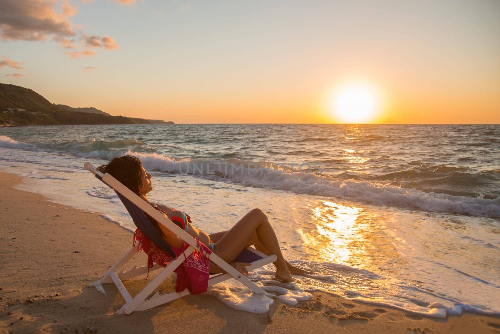 woman lying on the beach near the sea at sunset