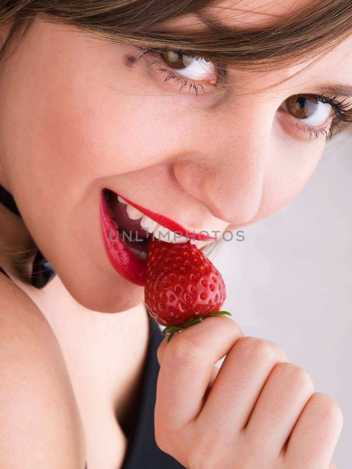 Young woman eating strawberry