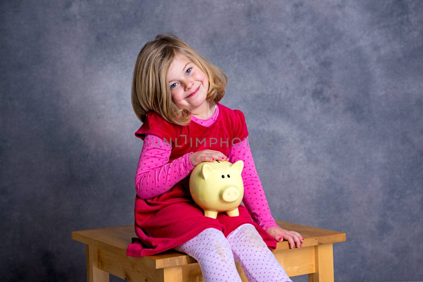 portrait of a smiling girl with piggy bank