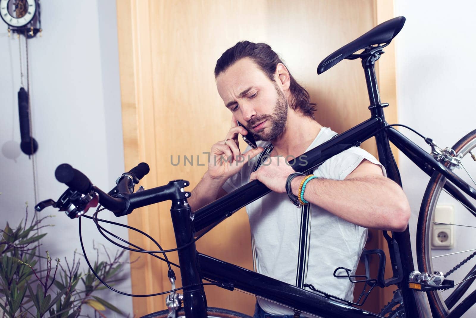 young bearded man calling with bike on the shoulder