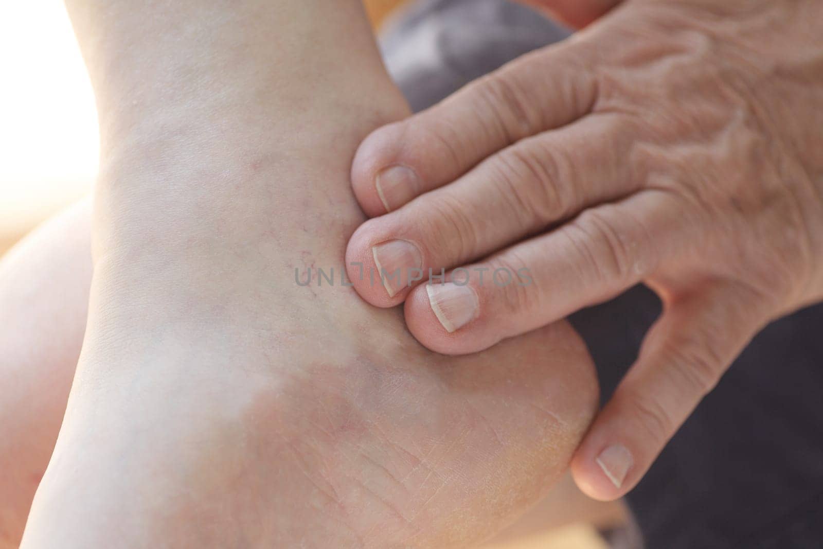 A man puts his fingers on his painful ankle.