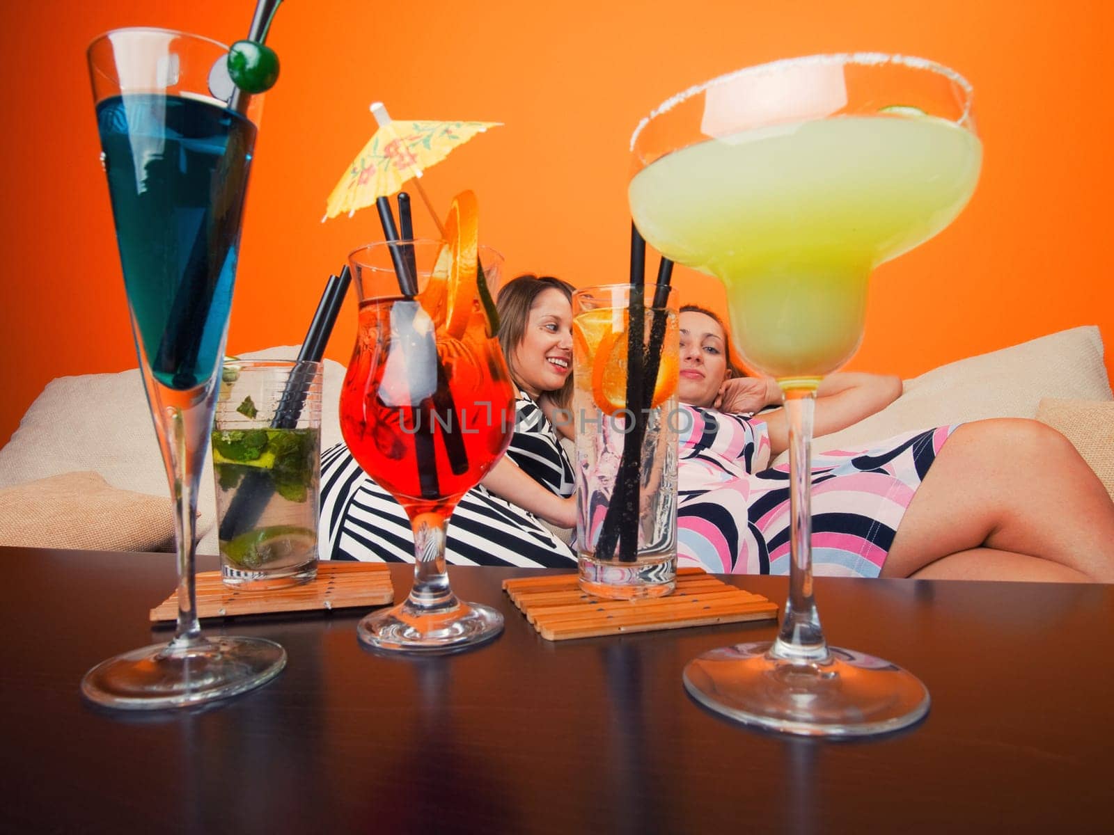 Girls on the sofa with cocktails, wide angle