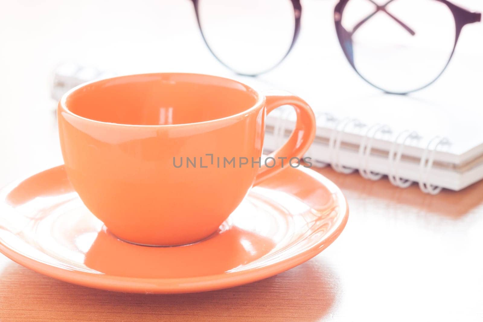 Close up of coffee cup with book and eyeglasses, stock photo