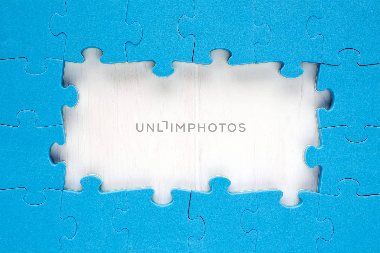 Blue jigsaw puzzle pieces arranged as a border around a wooden surface  with space for your text