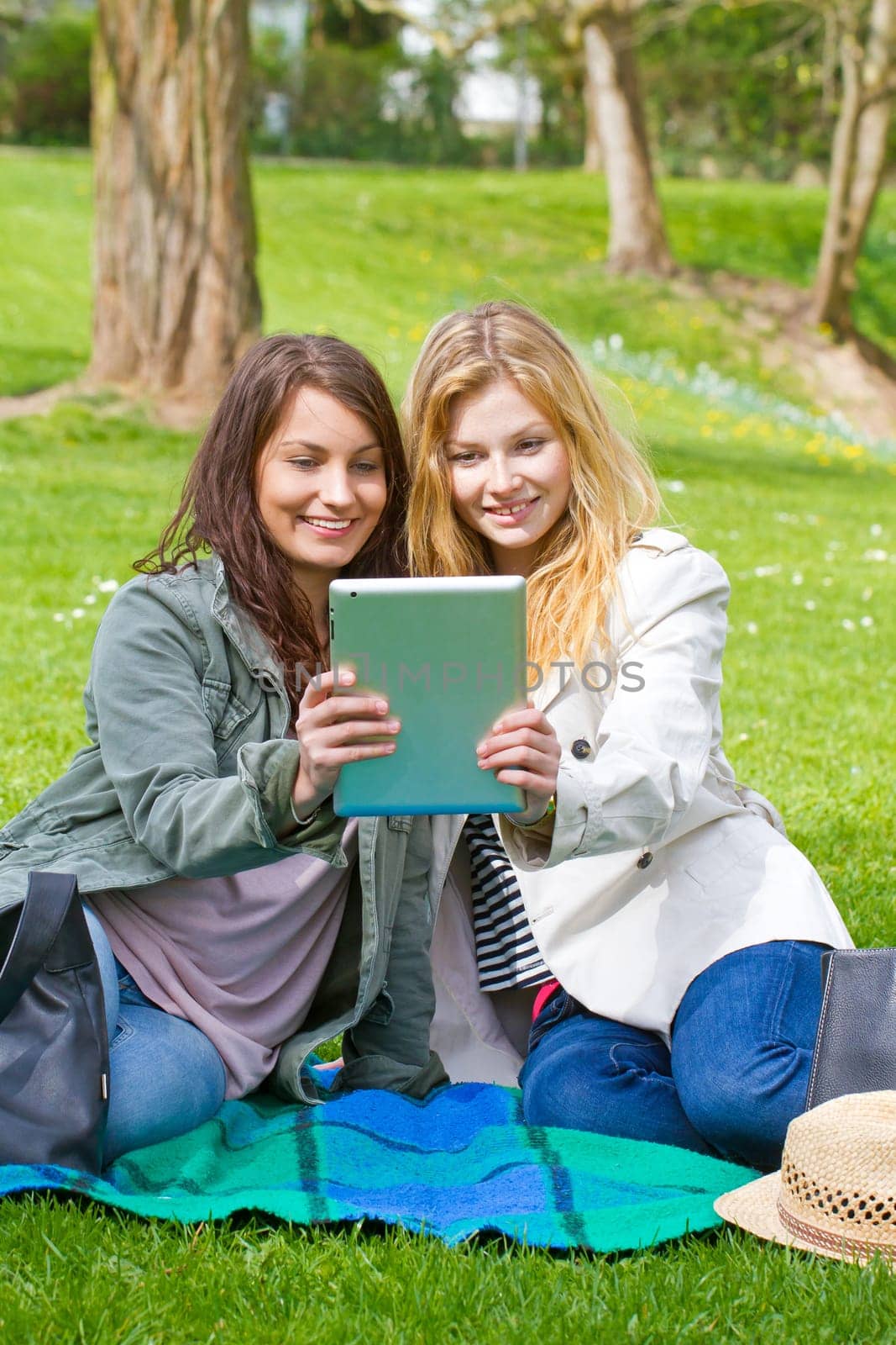 two friends with tablet in park