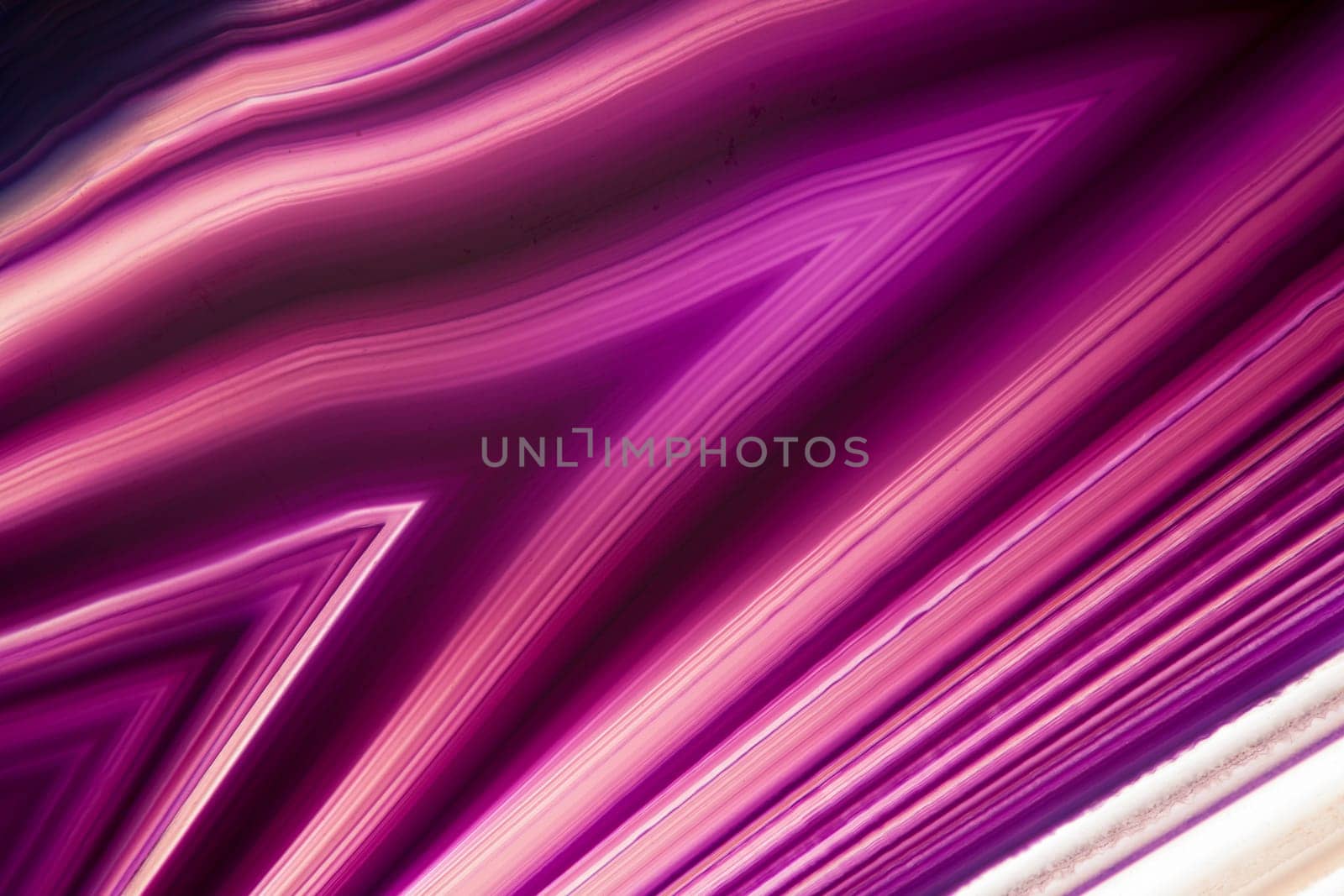 format-filling detail view of a flat,polished and transparent disc of an agate with arrow-shaped structures in violet