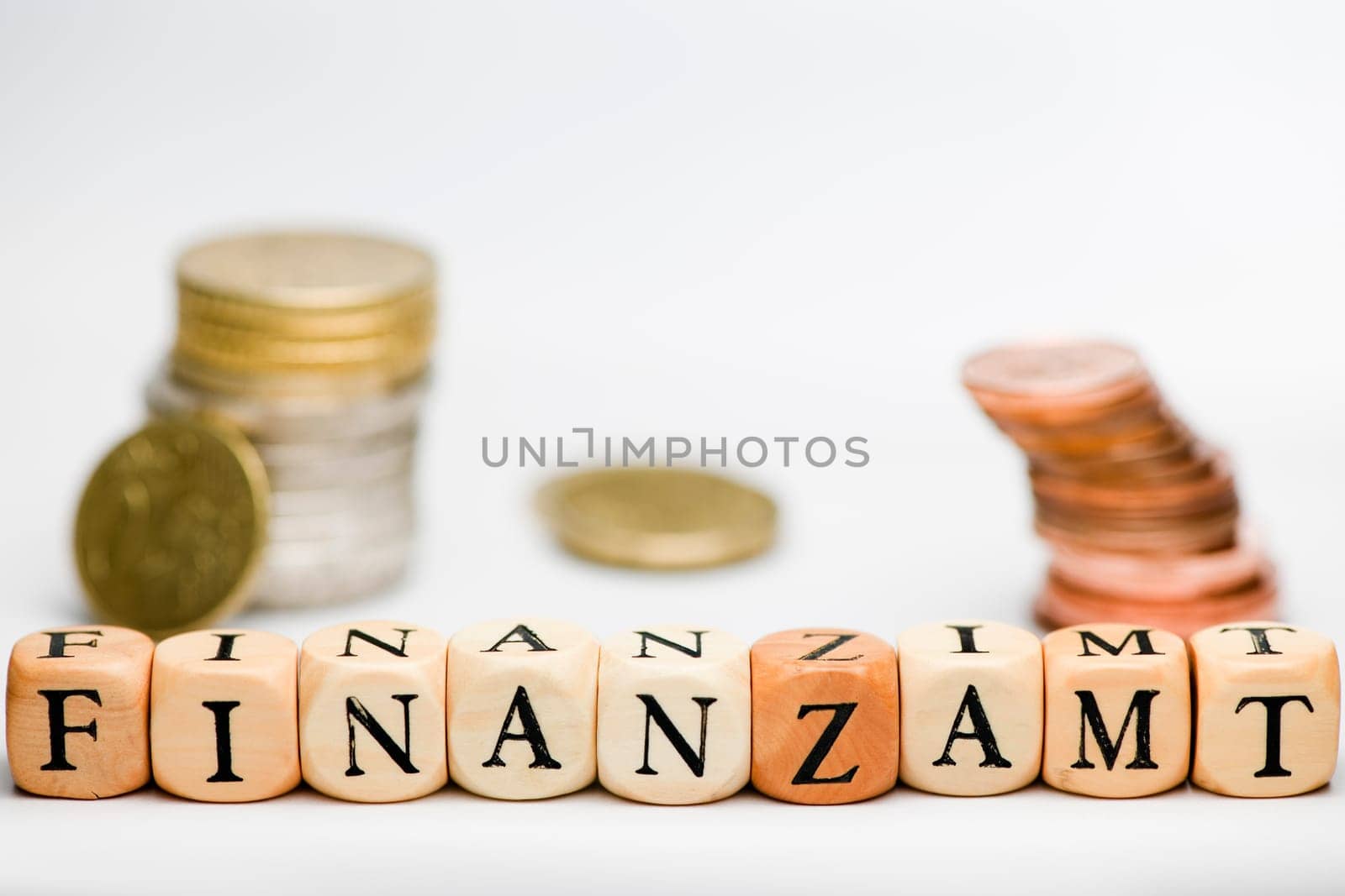 A series of letter cubes representing the word "TAX OFFICE"" with small fuzzy stacked coin on white background"