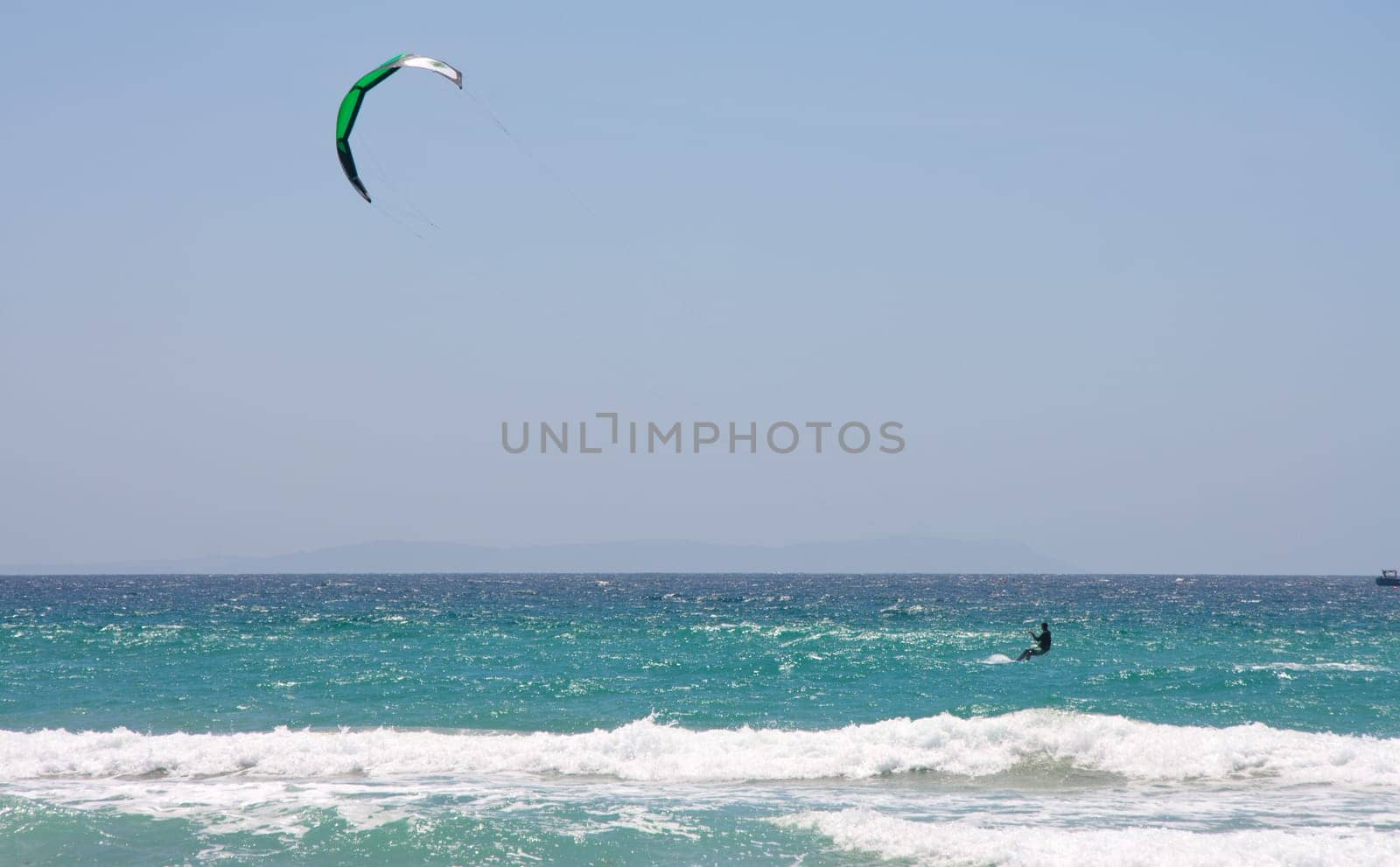 Sportsman kite surfer on clean beach in windy day, Tarifa, Spain
