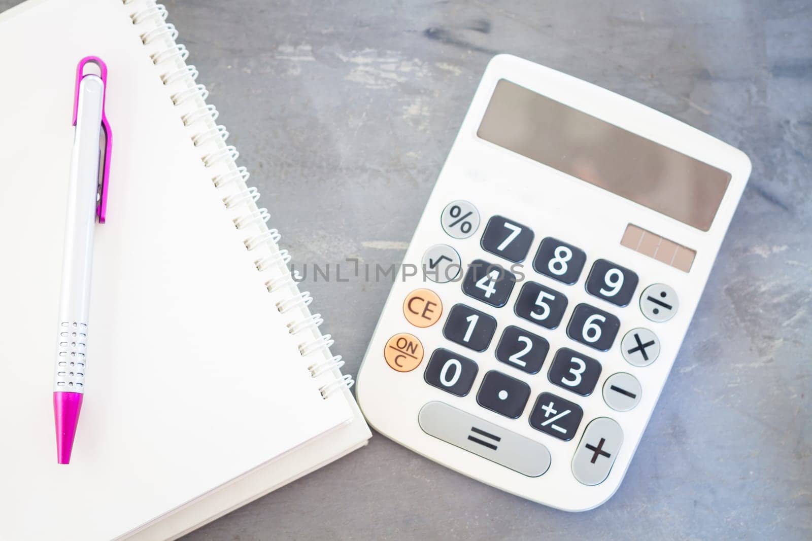 Calculator, notepad and pen on grey background, stock photo