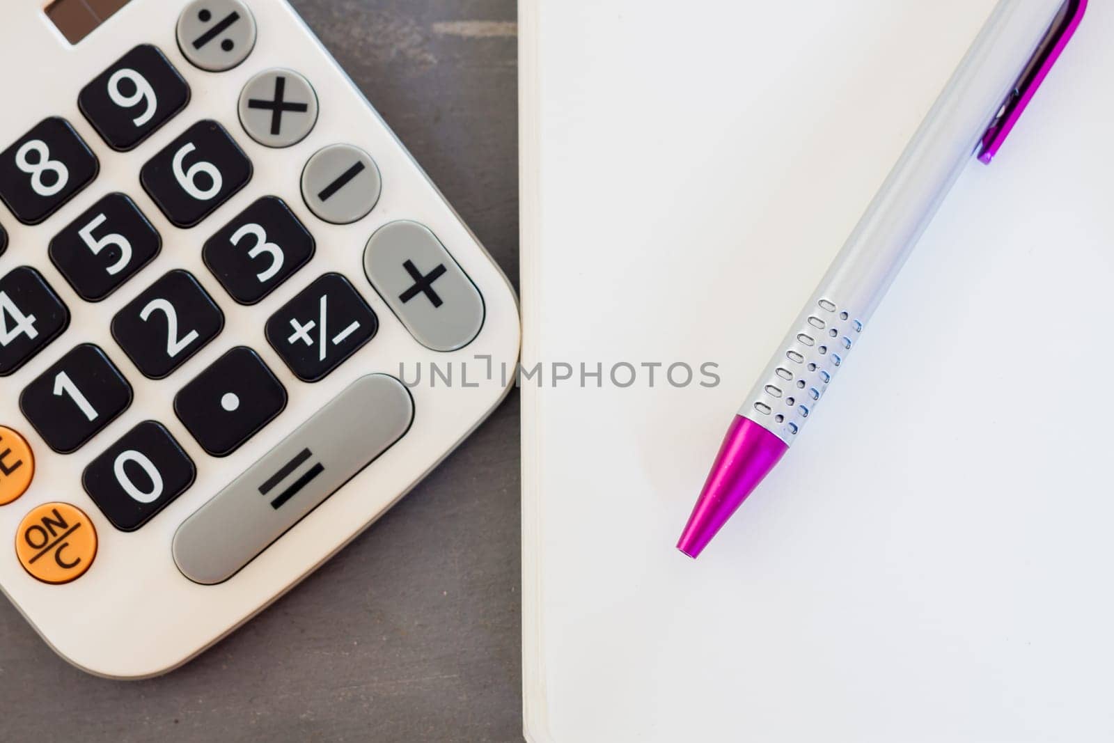 Calculator, notepad and pen on grey background, stock photo