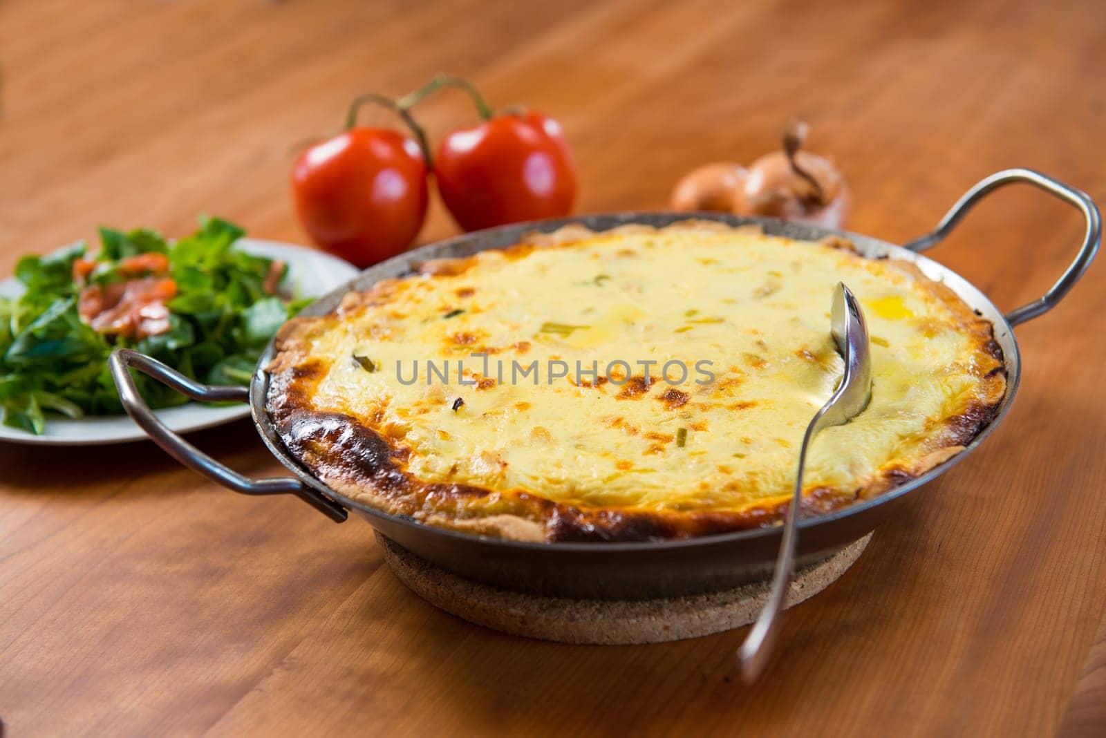 baked quiche with field salad on wooden table
