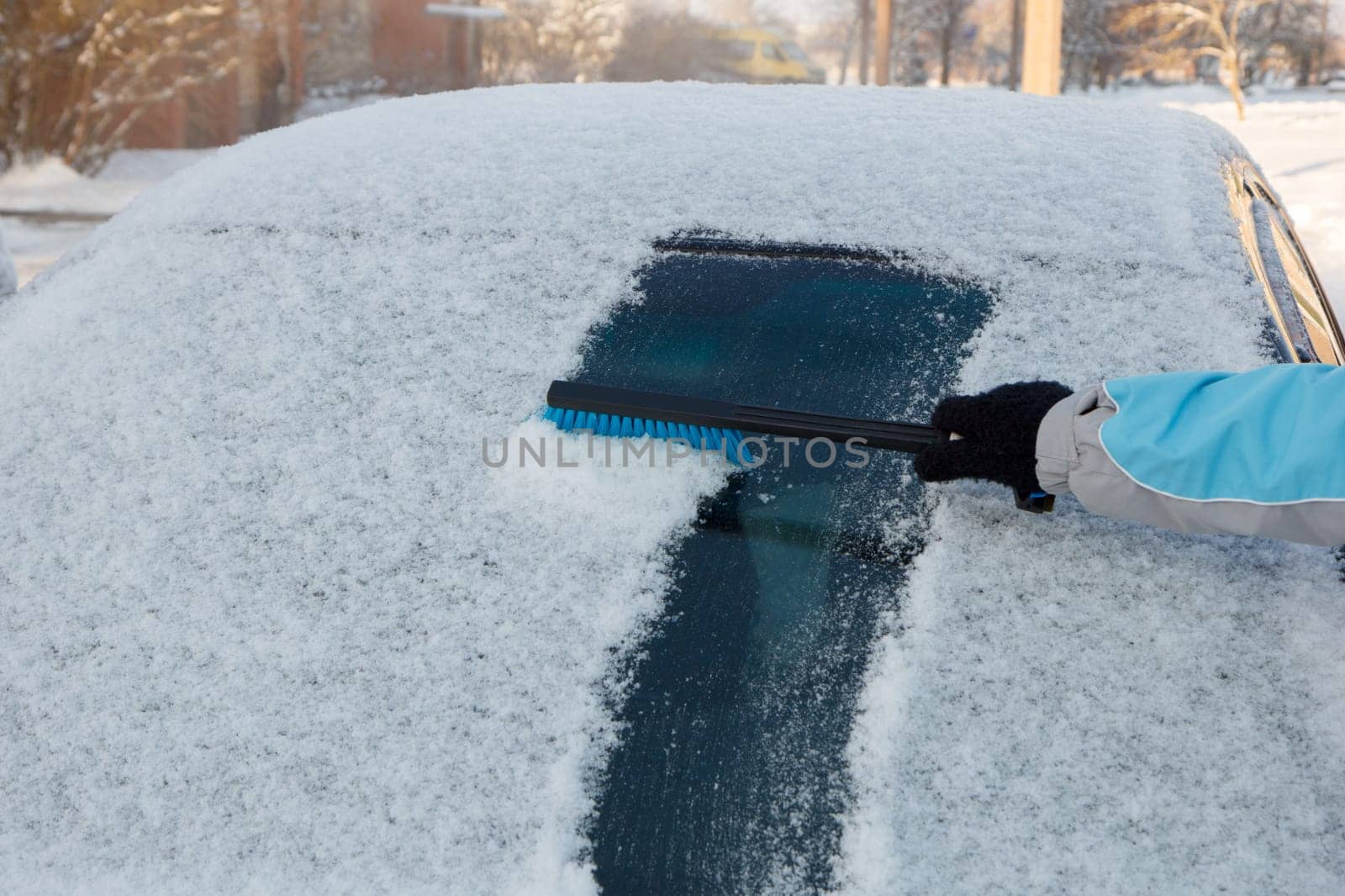 Snow being cleared off from a car front window