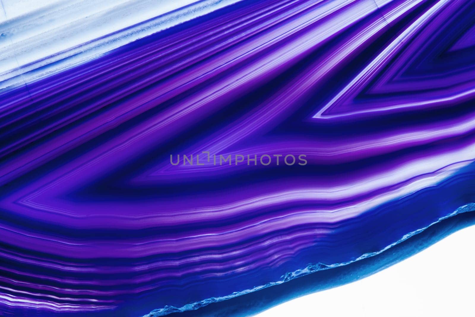 Detailed view of a flat,polished and transparent disc of an agate with arrow-shaped structures in blue against a white background