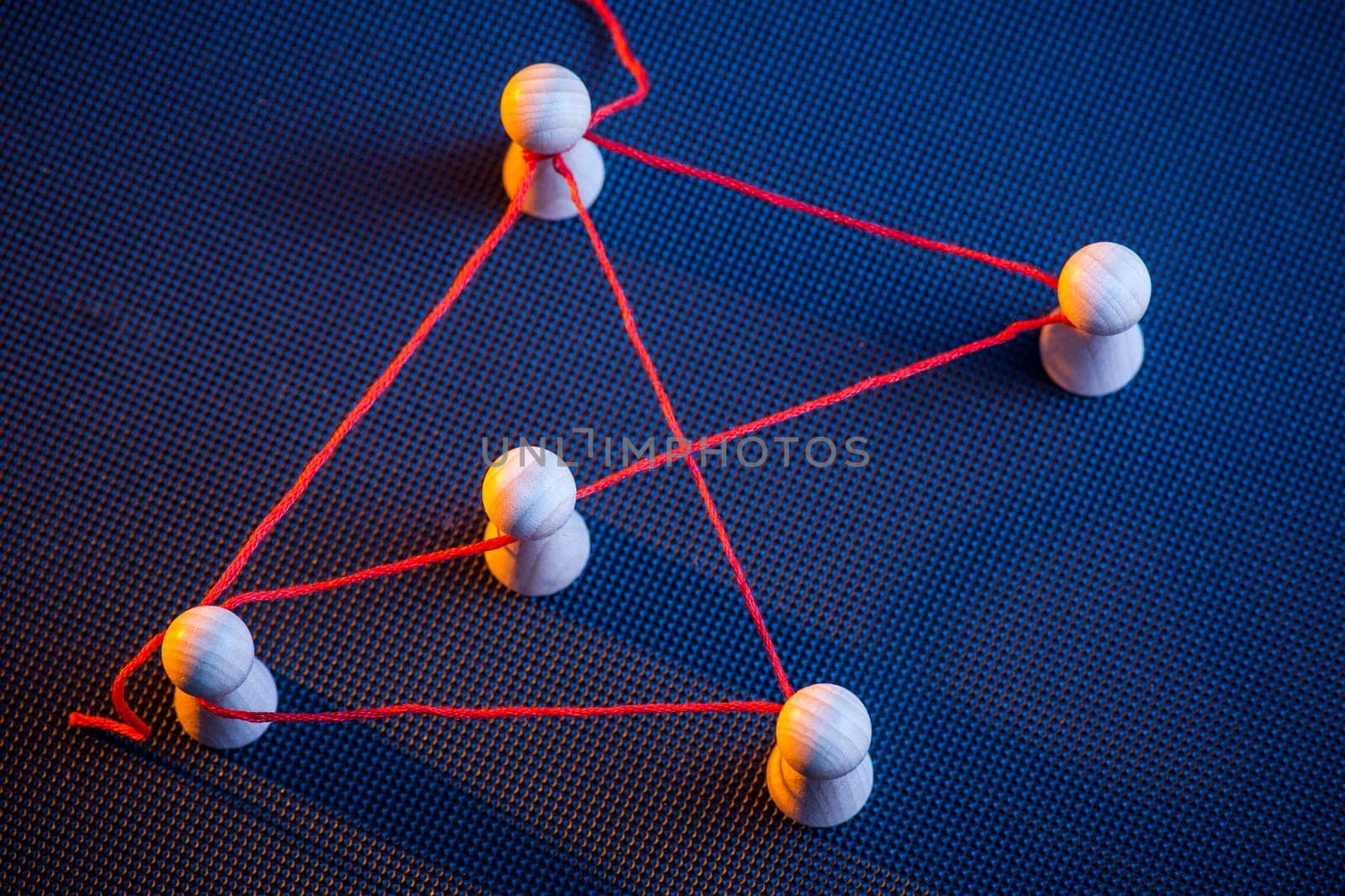 increased detailed view with red thread connected Ludo tiles on dark-puped ground in the side light in red and blue