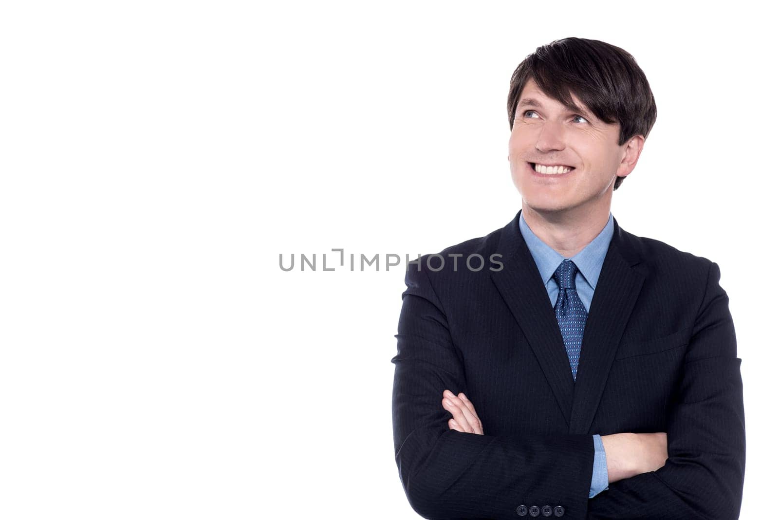 Pensive businessman looking up with folded arms