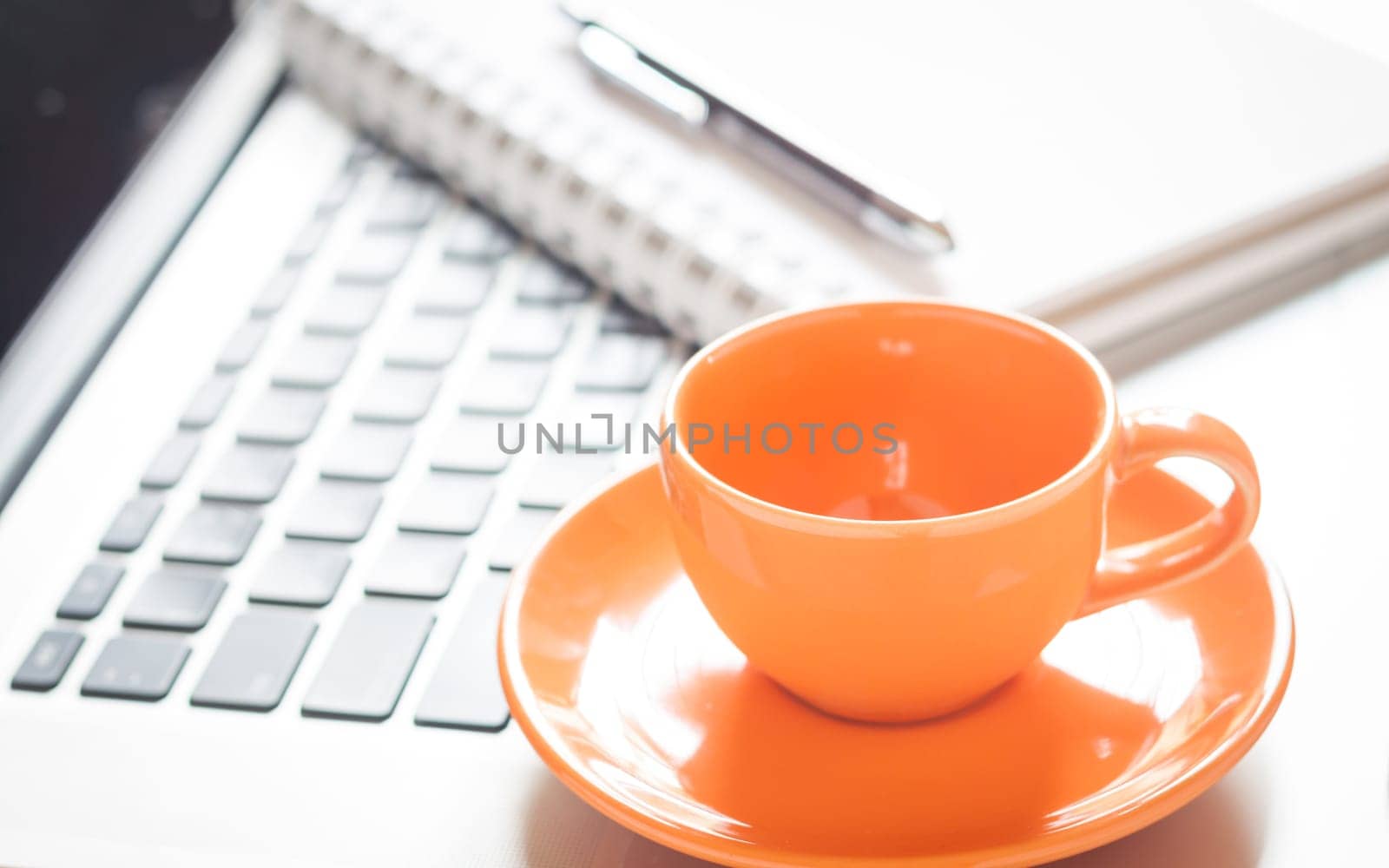 Laptop with coffee cup and notepad on desk, stock photo