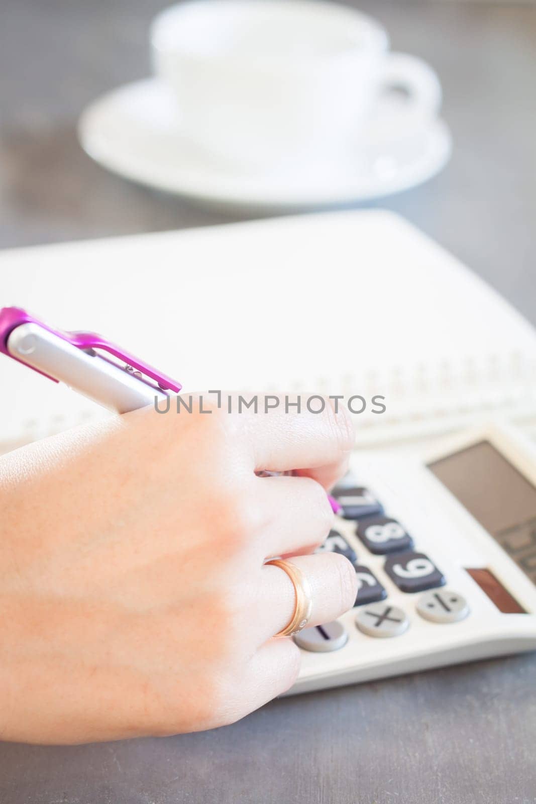 Hand holding pen and pressing calculator buttons, stock photo