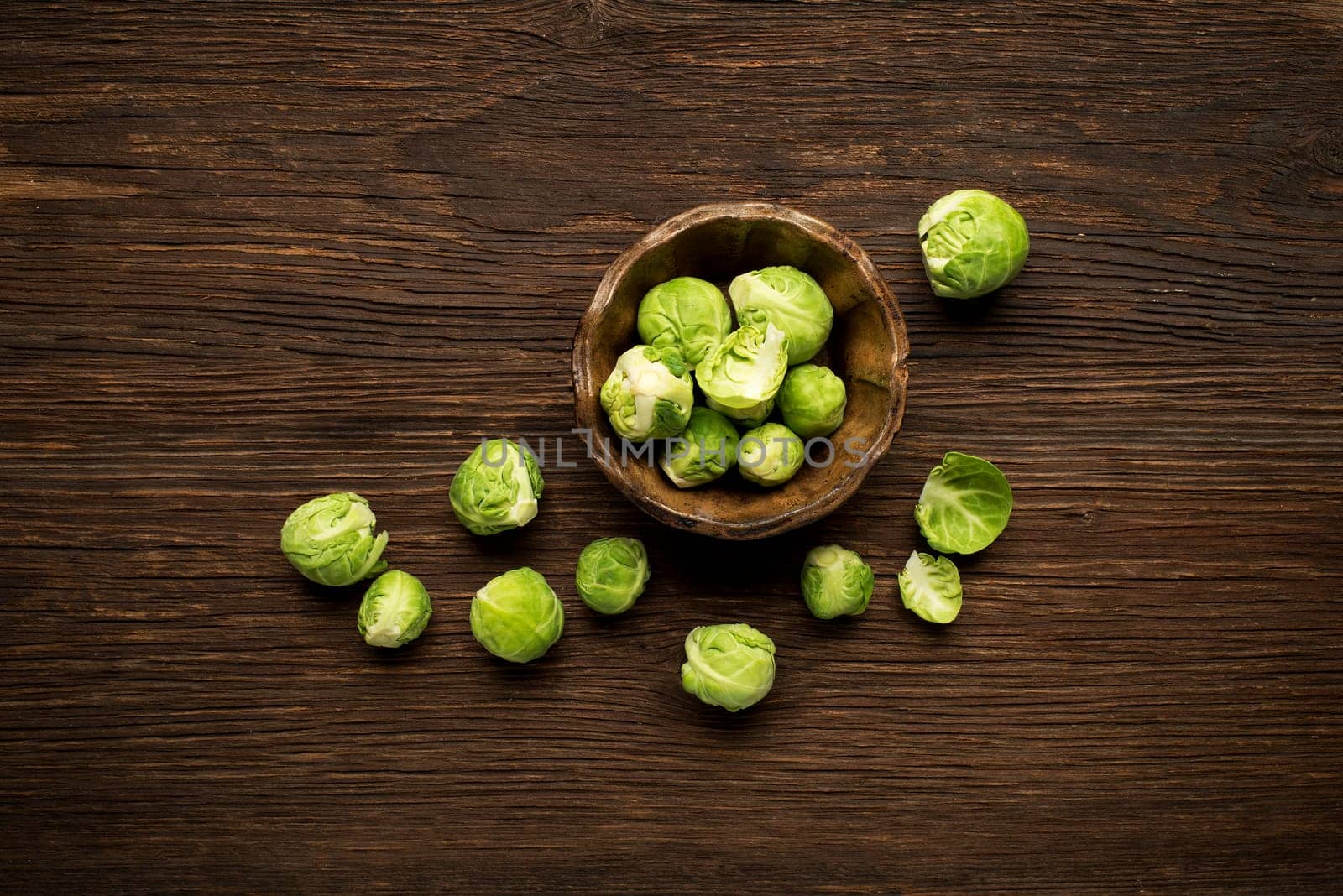 Bunch of fresh Brussels sprouts in a cup on wooden background.