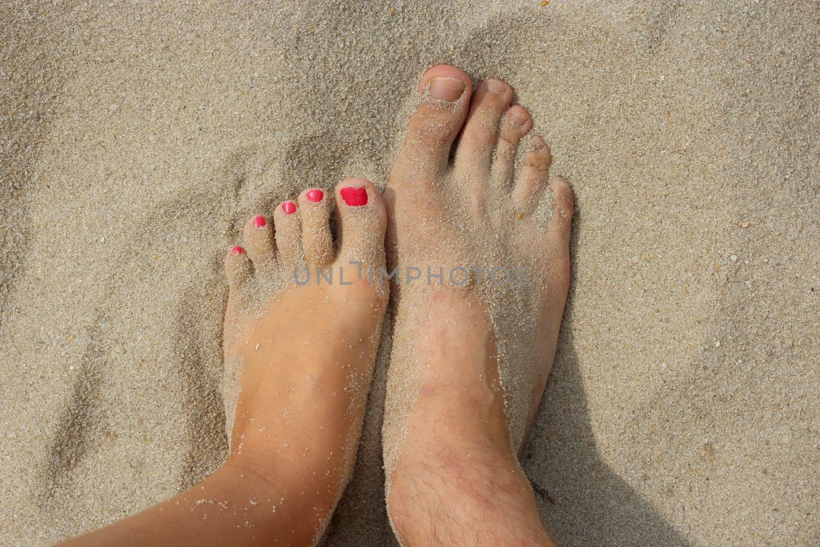 feet of father and his modern teen daughter on the sand