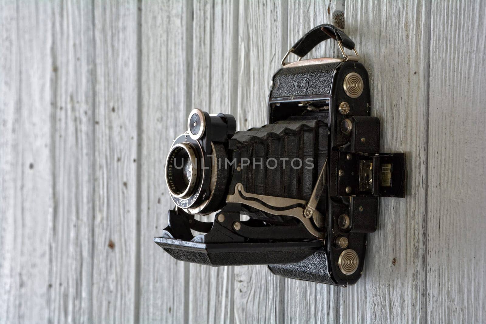 Black old camera hangs on old,white painted wooden wall