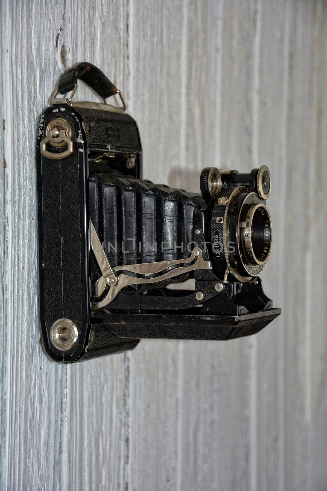 Black old camera hangs on old,white painted wooden wall