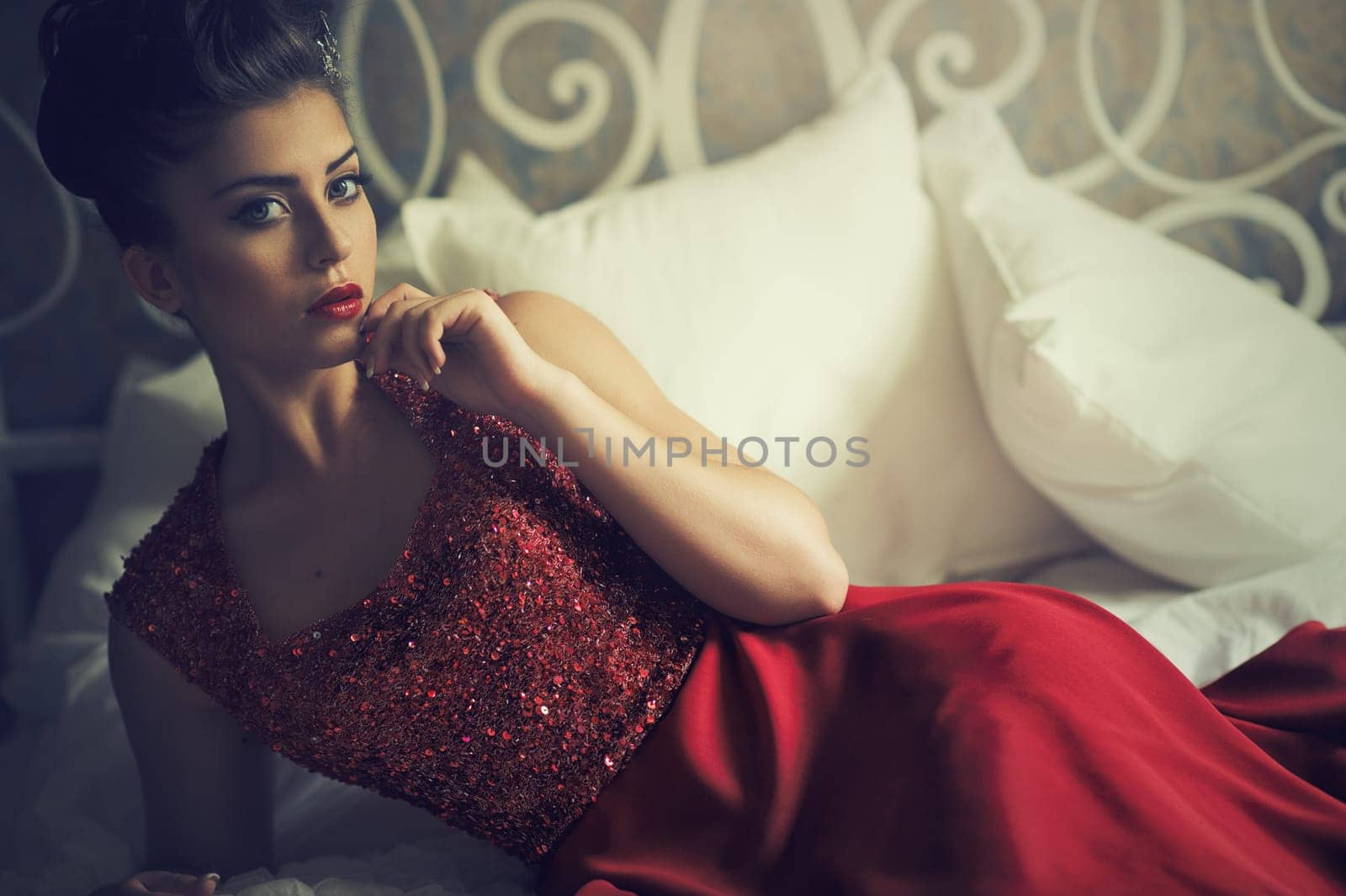 Attractive brunette woman lying on sofa in elegant red dress