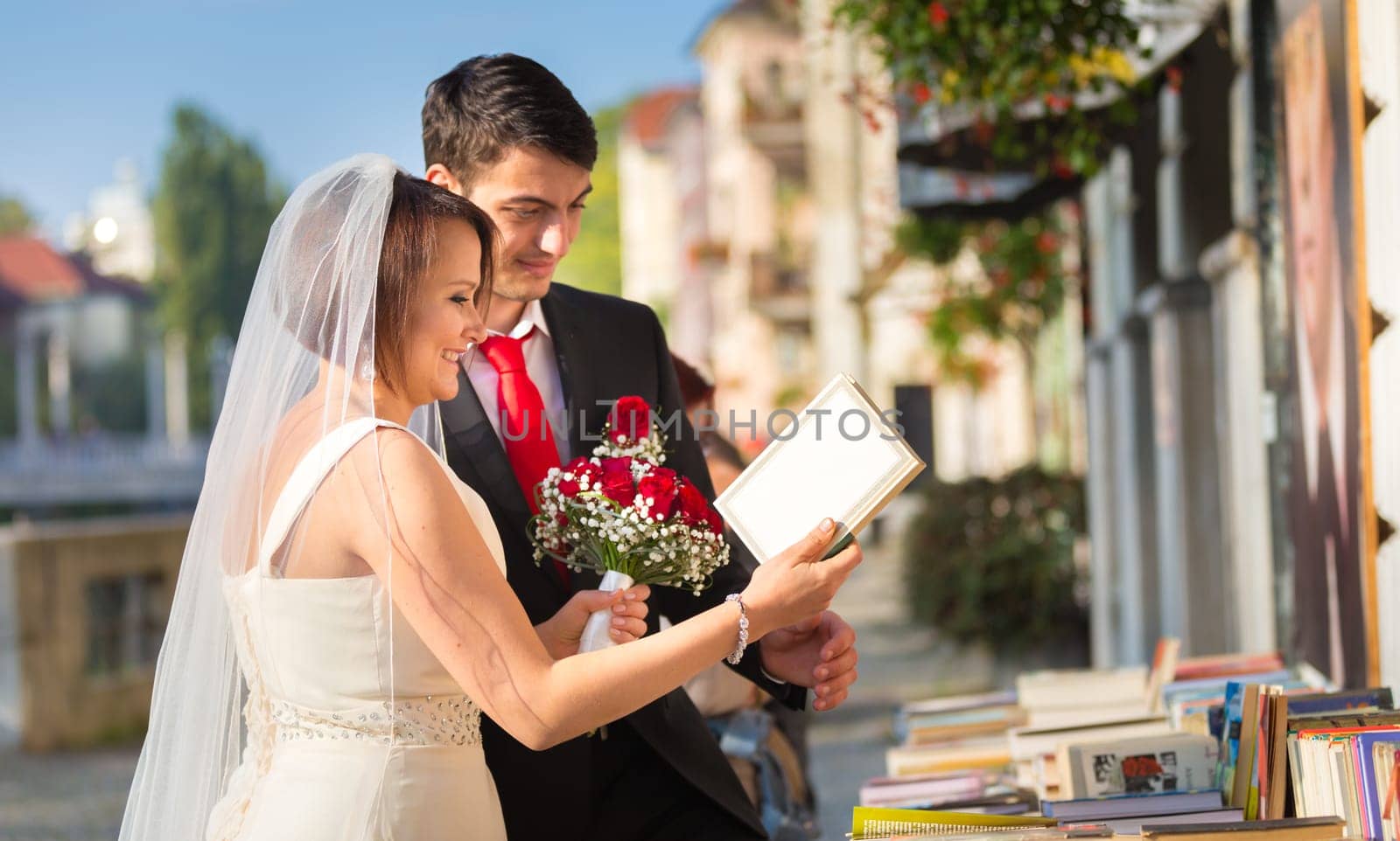 Bride and groom. Portrait of a loving wedding couple reviewing vintage books in antique book shop in medieval city center of Ljubljana, Slovenia.
