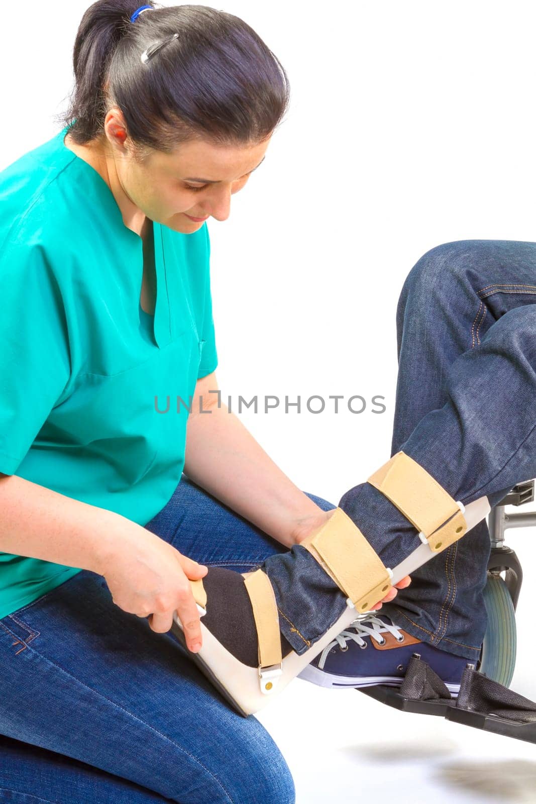 Orthopedist puts orthosis to patient in wheelchair with disabilities