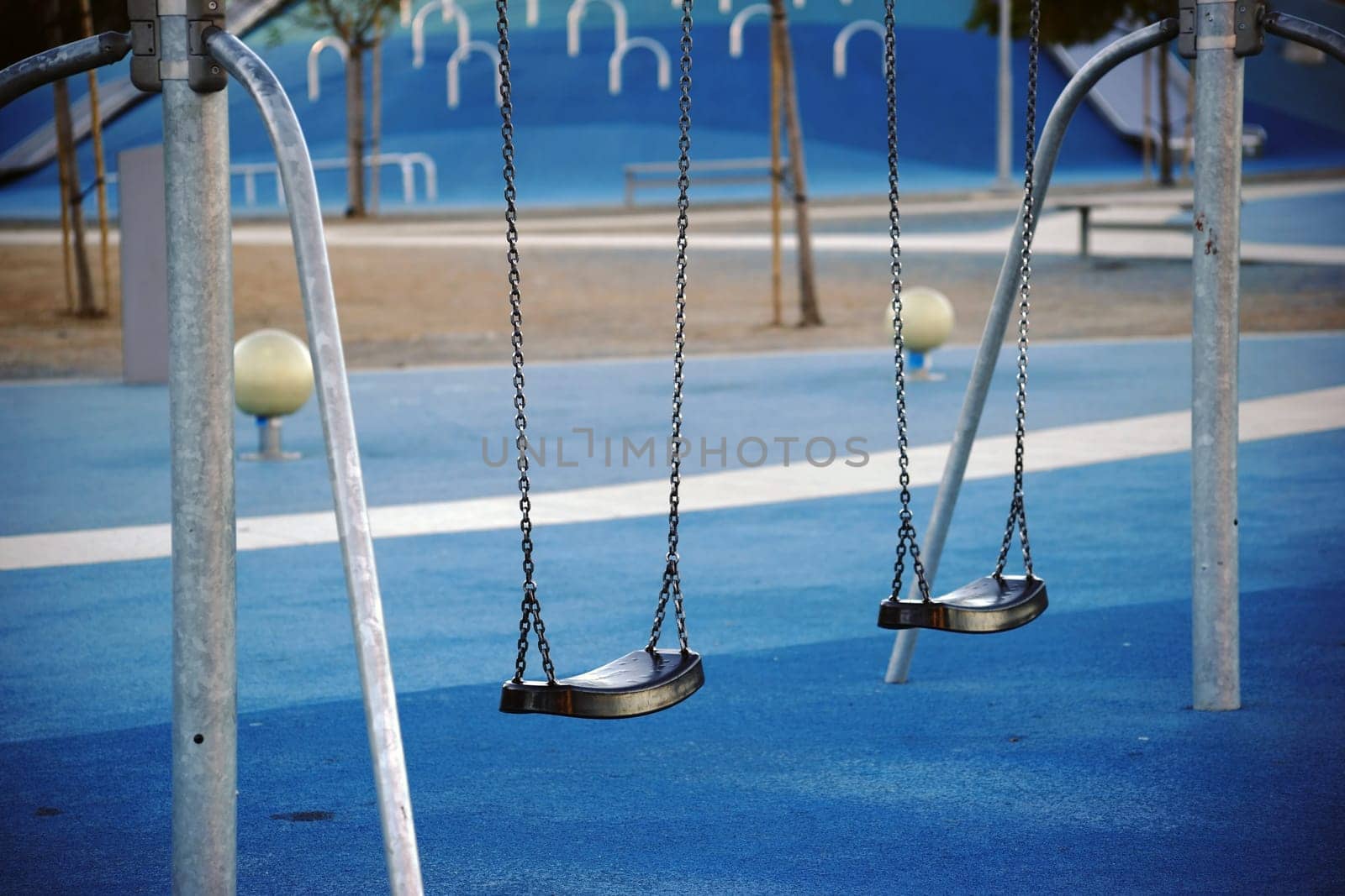 A modern playground in the city with laid rubber mats,swings and slides.