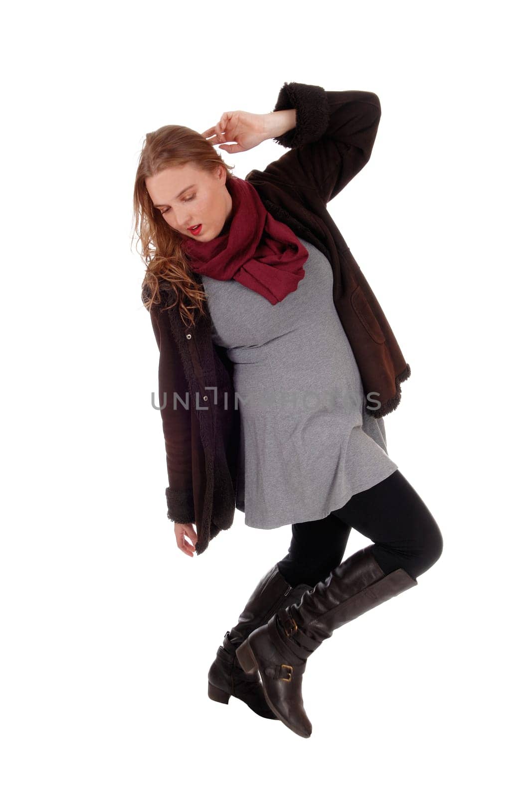 A beautiful young woman dancing in a winter coat and black long boots.and burgundy scarf, isolated for white background..