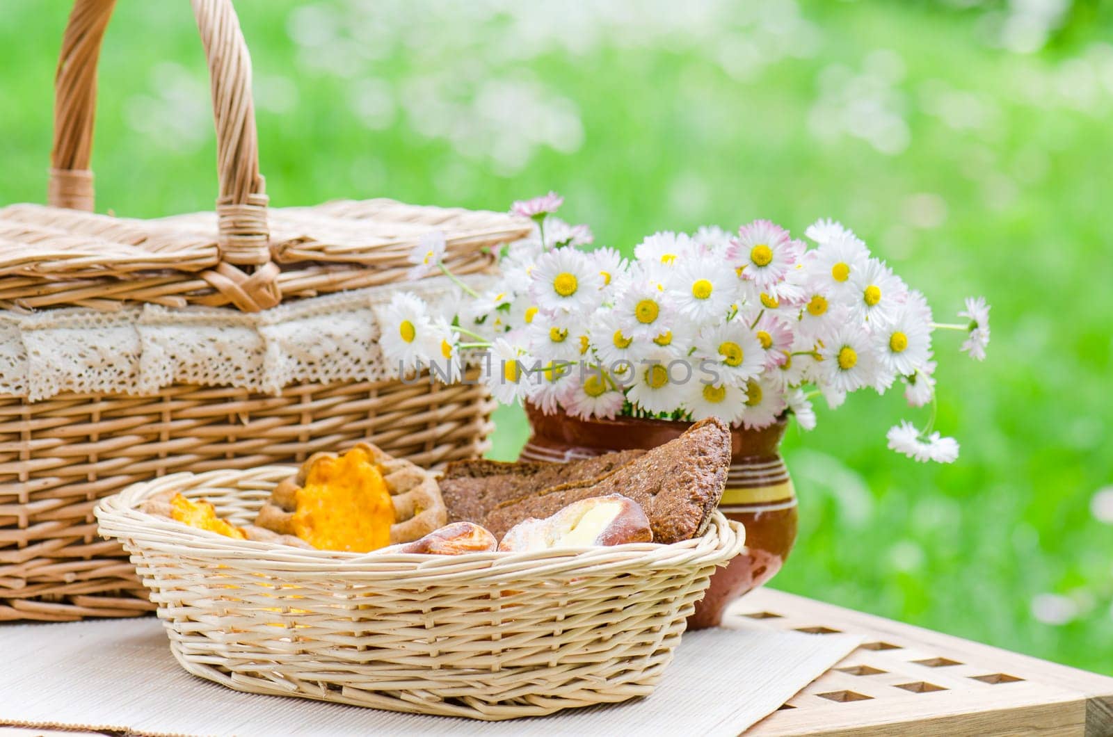 Buns in a wicker basket and a bouquet of flowers