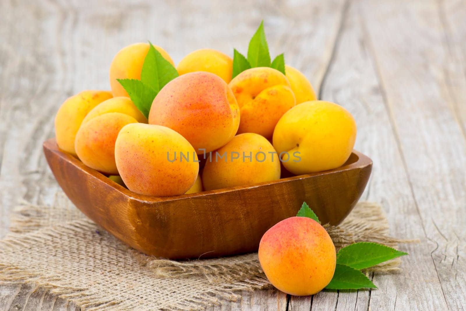 fresh apricots in a bowl on wooden background