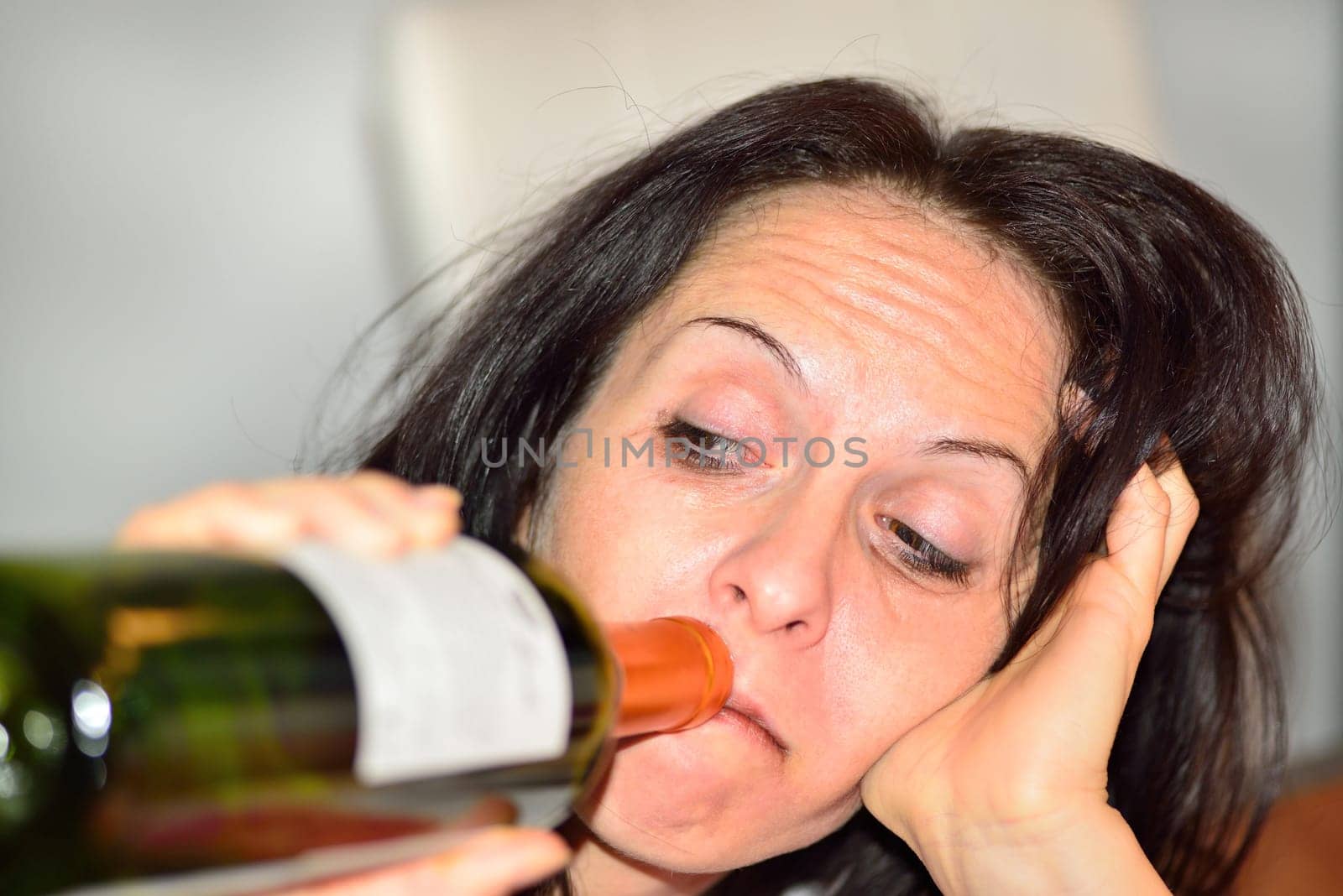 Young drunk woman with a bottle of red wine