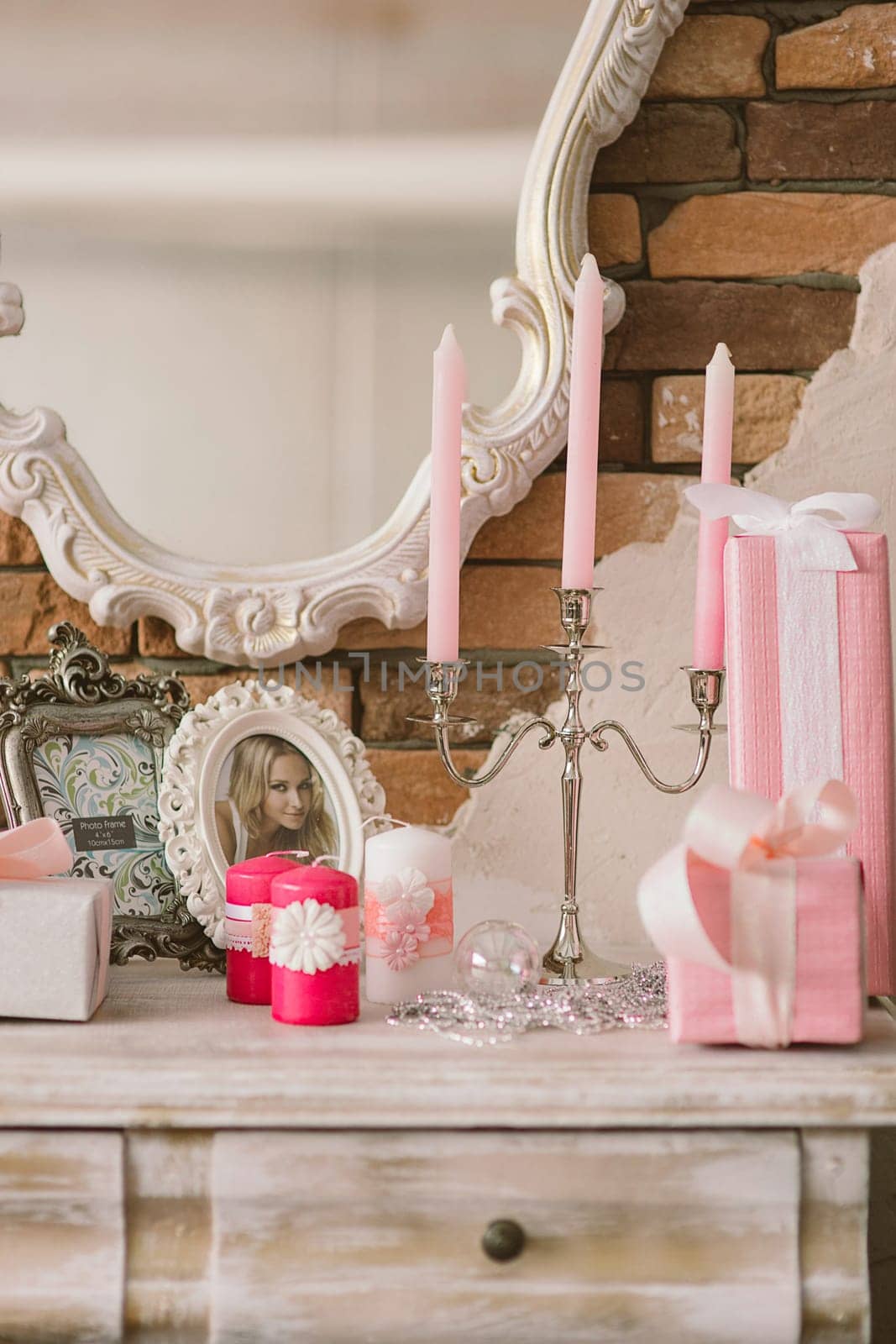 New Year's and Christmas interior in pink color with a dresser, a wall mirror, gifts, candles