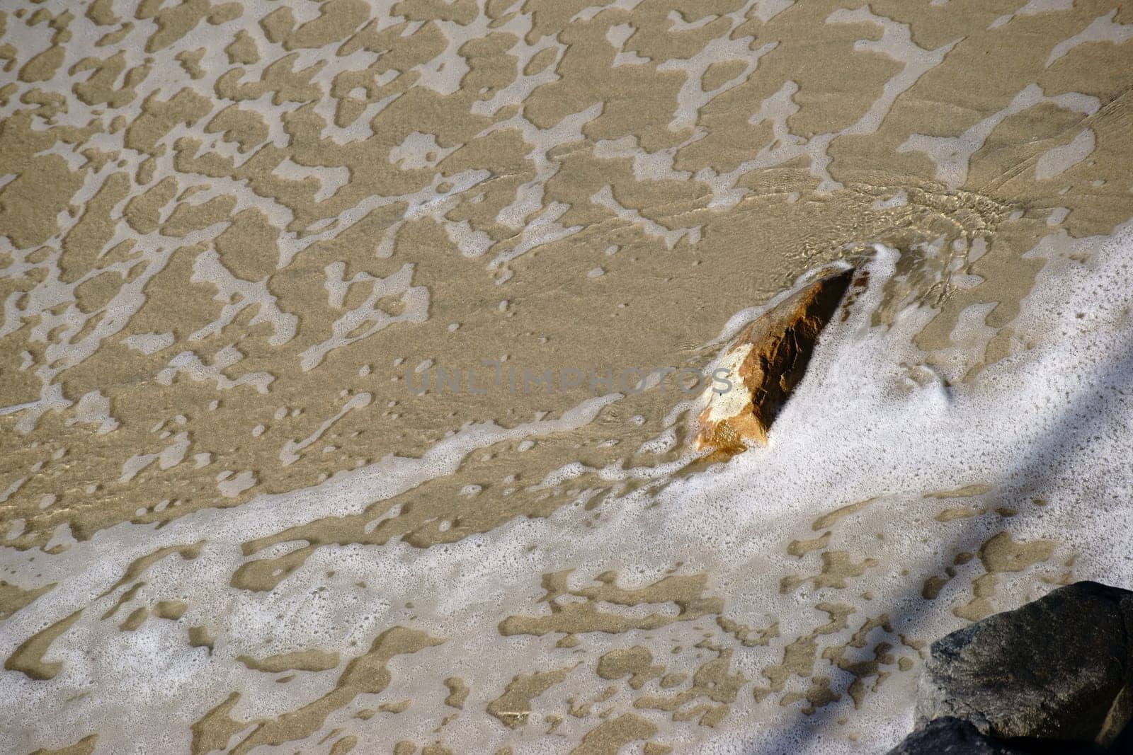 Seawater on the coast surrounds large boulders.