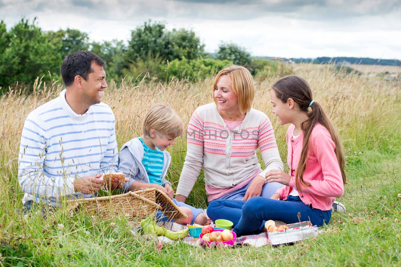 A family of four are sat on the sand dunes having a picnic